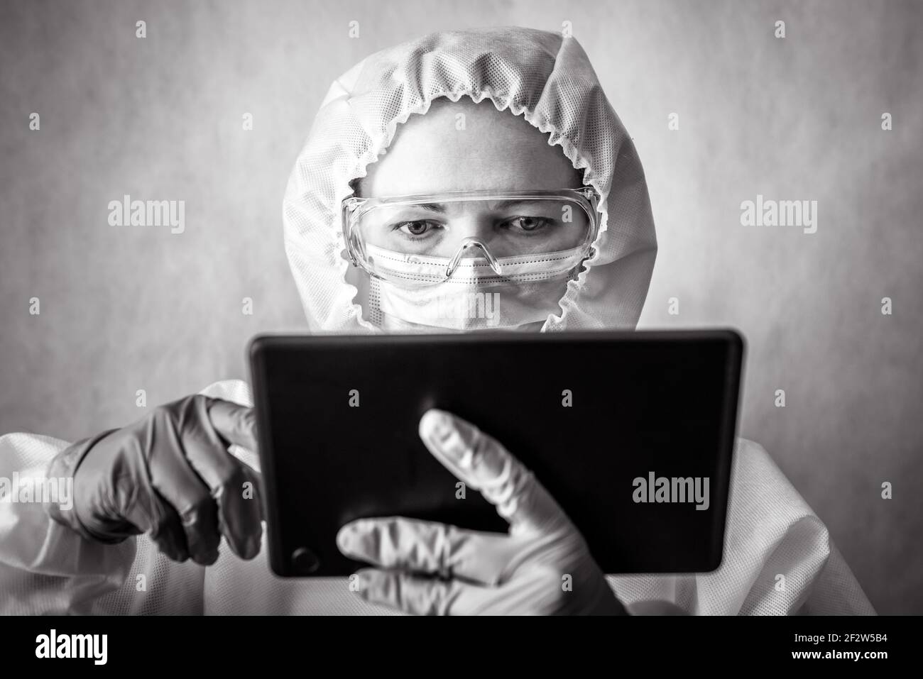 COVID-19 coronavirus concept, doctor uses digital tablet, portrait of nurse wearing goggles and mask due to corona virus, physician in personal protec Stock Photo