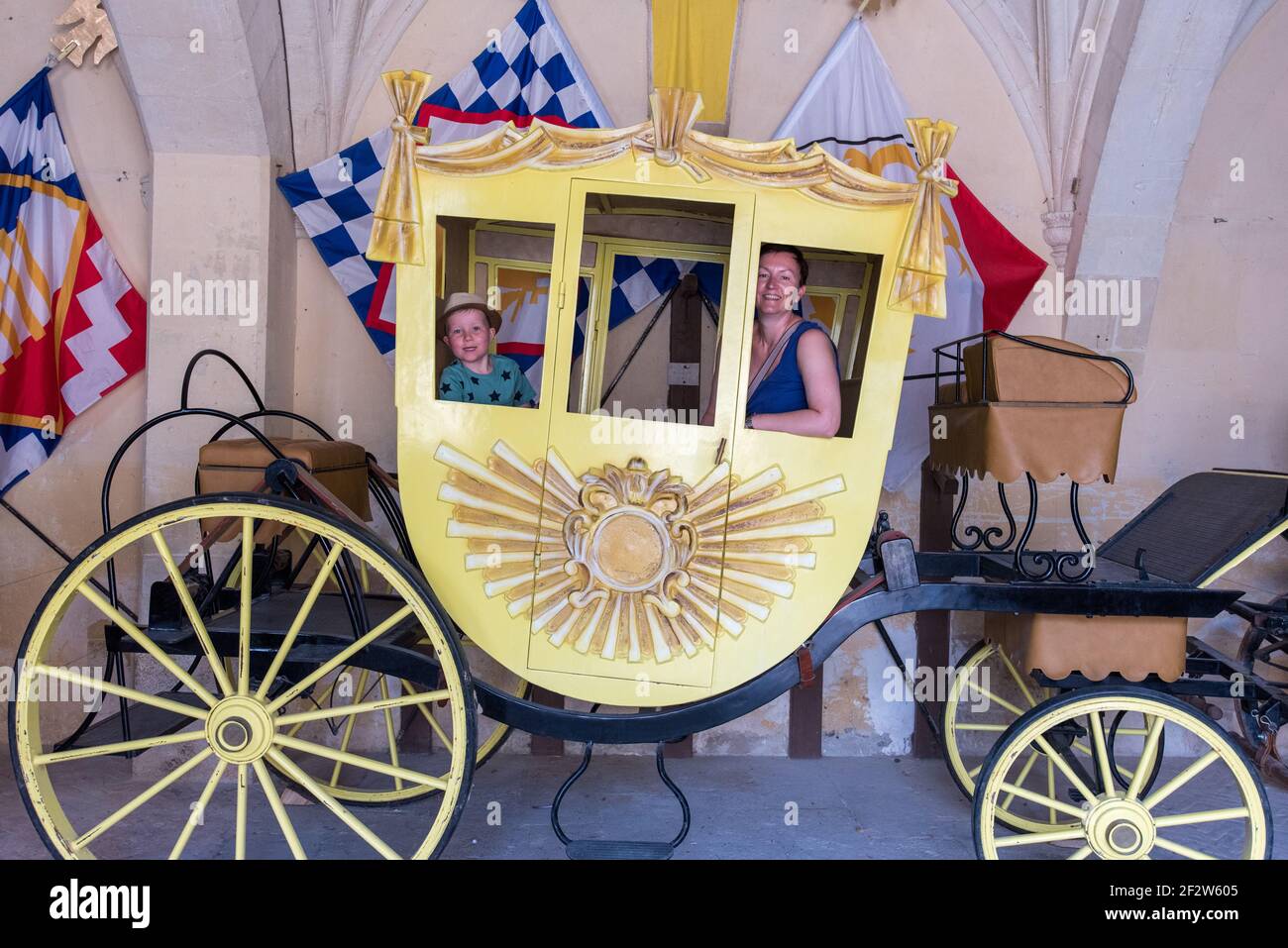 A mother and son pose for picture in a yellow four wheeled carriage. Stock Photo