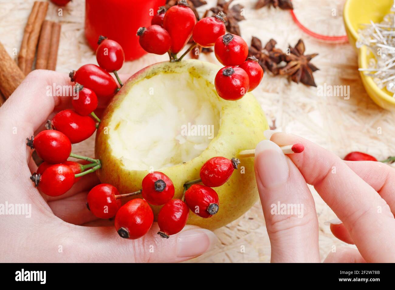 Florist at work: How to make apple and wild rose candle holders, autumn home decor - tutorial. Stock Photo