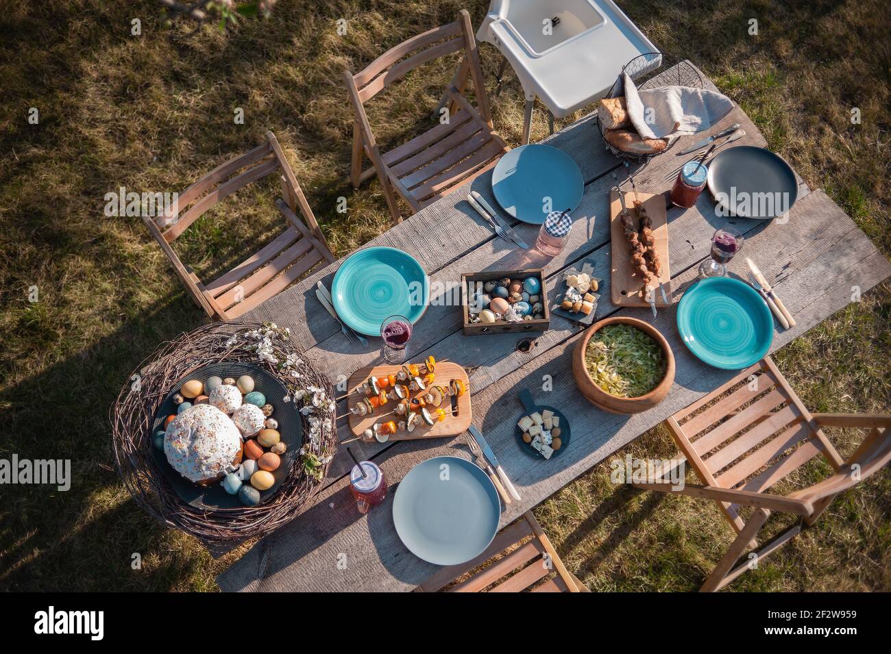 Wooden table in the garden, served with dishes and Easter cake Stock Photo