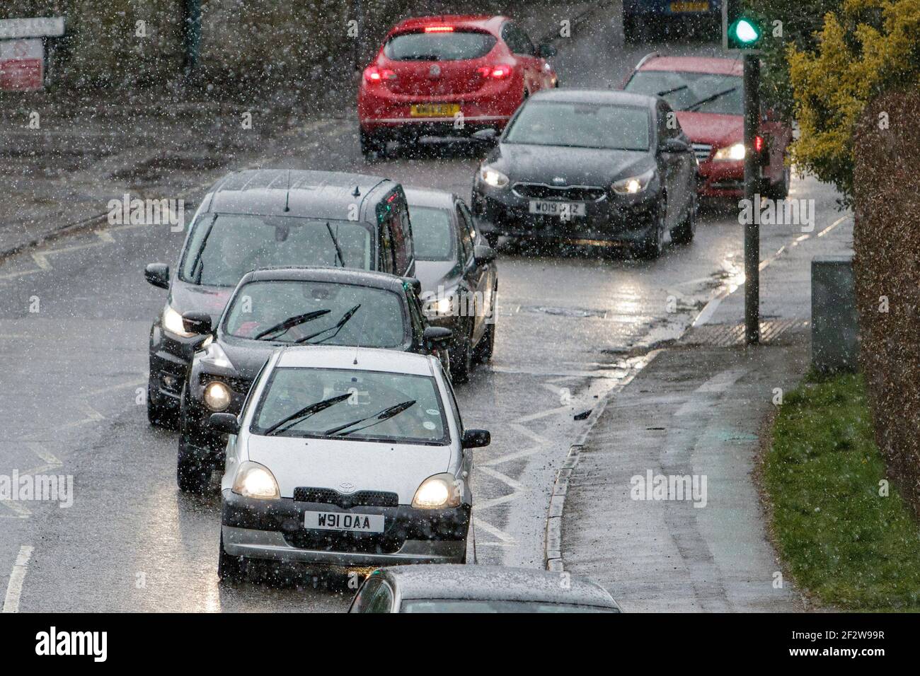 Chippenham, Wiltshire, UK, 13th March, 2021. Car drivers are pictured braving sleet showers in Chippenham as wintry showers make their way across Southern England. Credit: Lynchpics/Alamy Live News Stock Photo