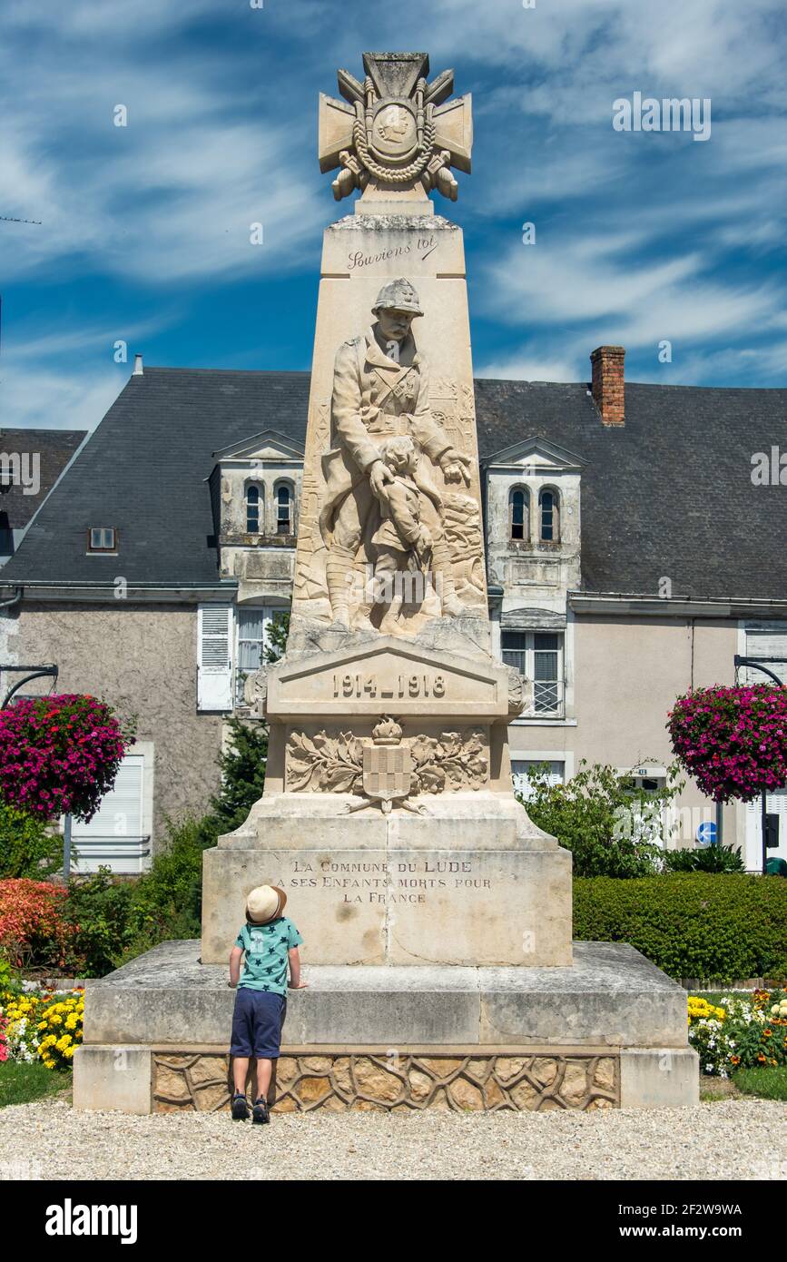 A little boy stands at the base of a monument to soldiers in the town of Le Lude in the Pays de La Loire Stock Photo
