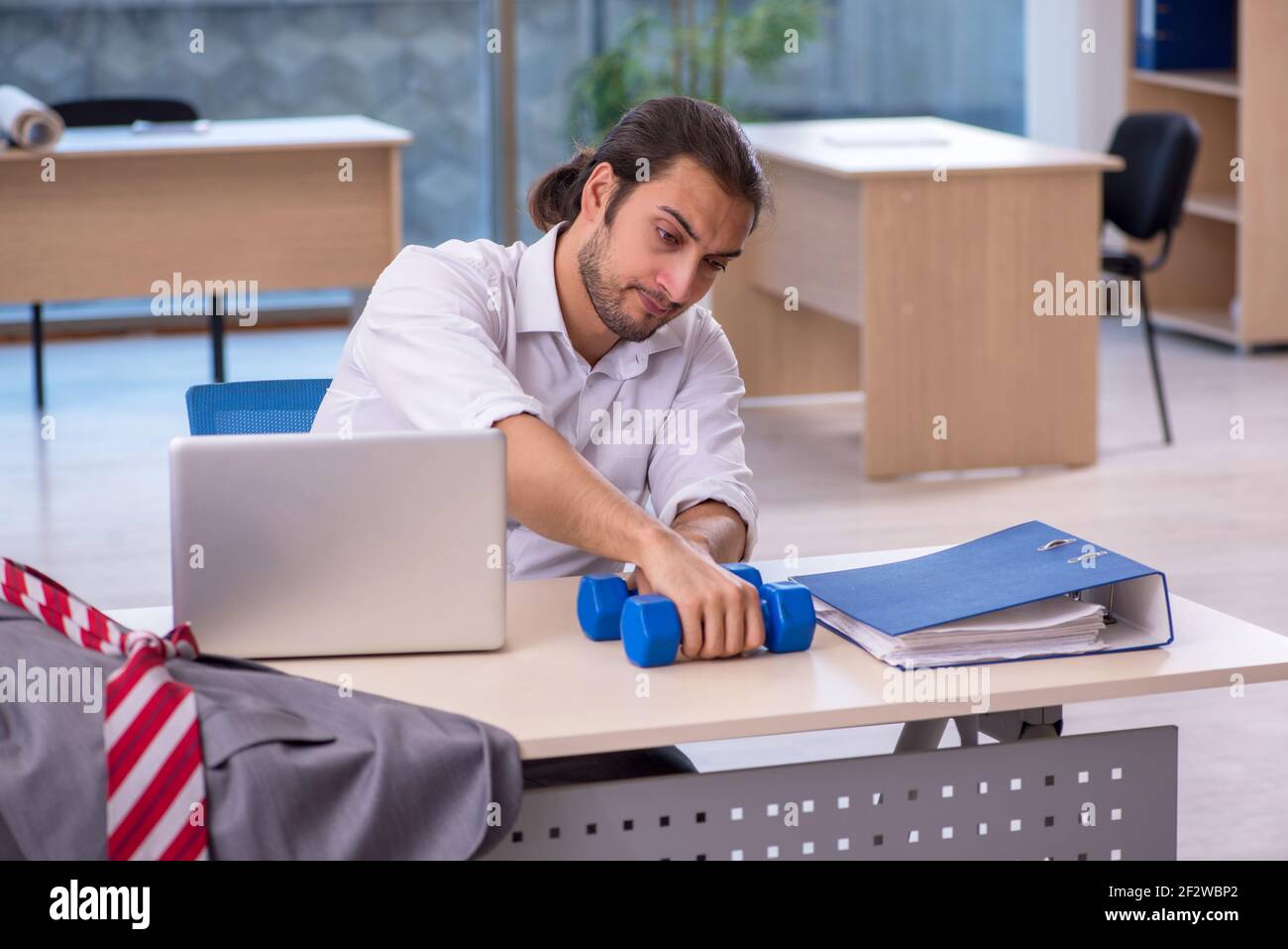 Young employee doing sport exercises at workplace Stock Photo - Alamy
