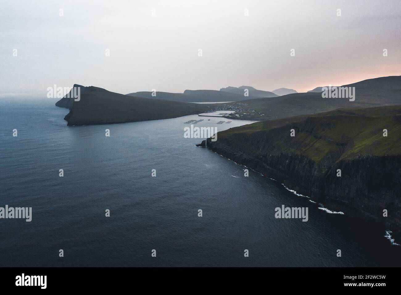 View from flying drone. Astonishing morning scene of Vagar, Faroe Islands, Denmark, Europe. Amazing summer sunrise on Atlantic Ocean. Stock Photo