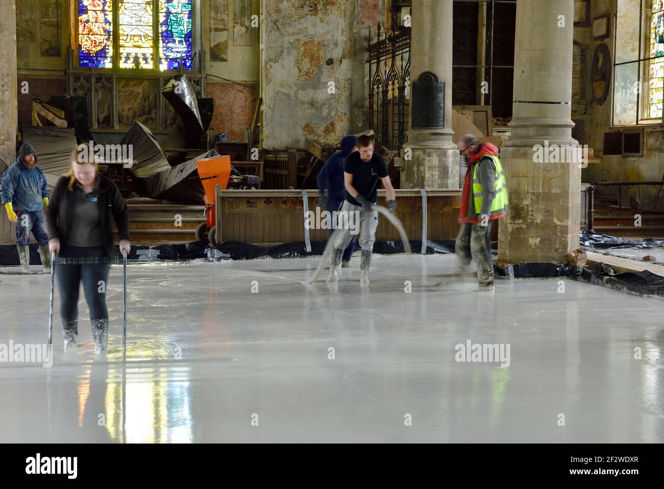 Workmen laying a eco-friendly poured self-levelling anhydrite floor screed, working in an old church Stock Photo