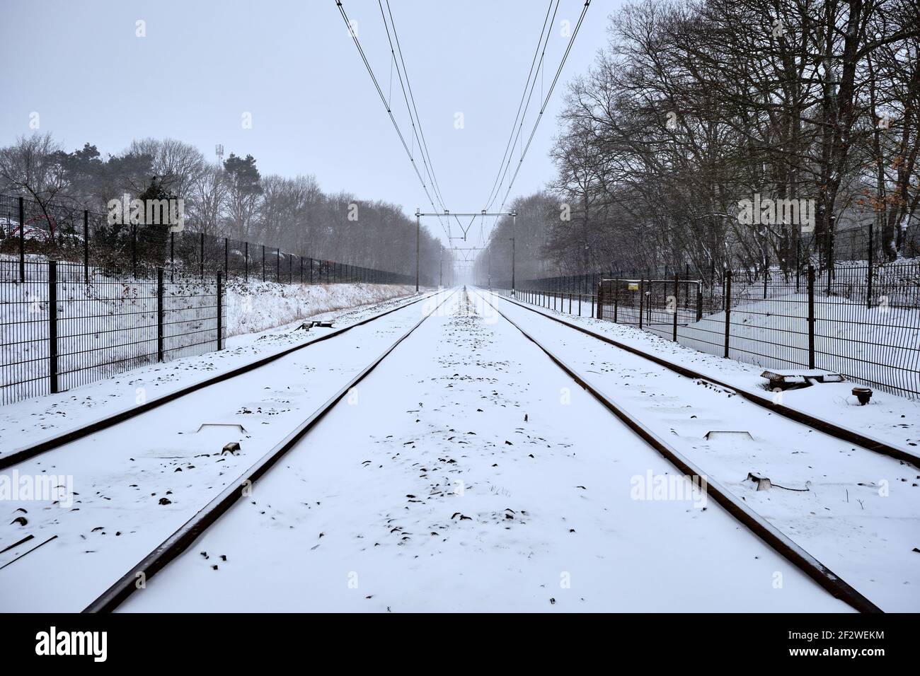 Railway tracks during snowfall in the Netherlands. Train tracks covered with snow in a snow shower near Amersfoort, Netherlands. Freezing rain and Stock Photo