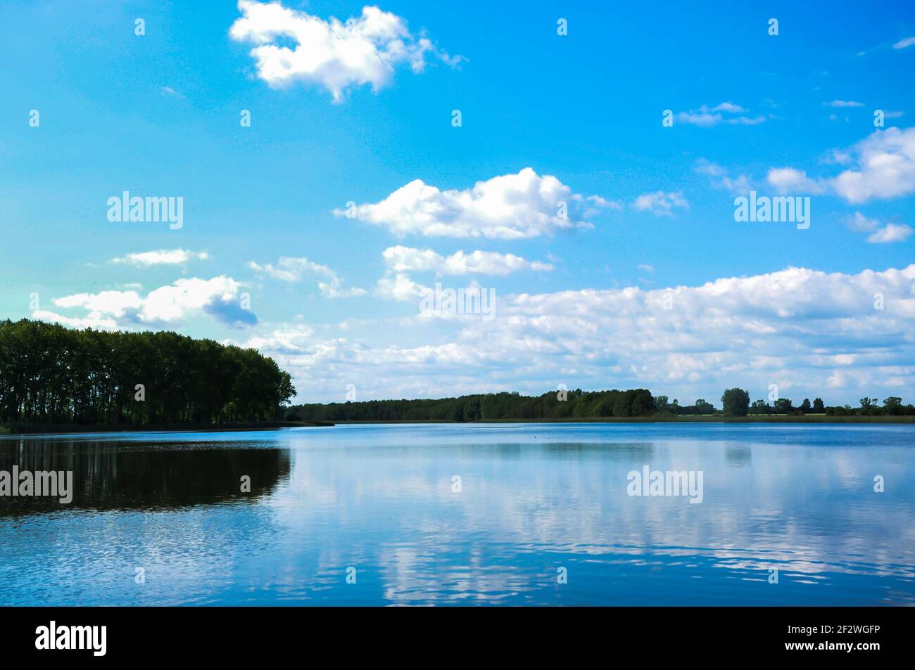 Big lake in a dreamlike blue with reflection of clouds Stock Photo