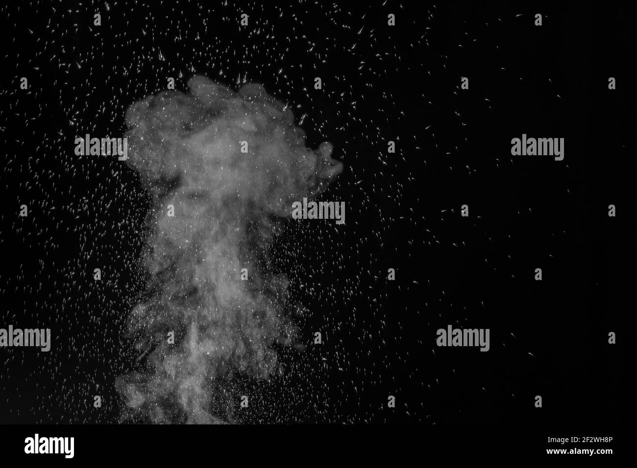 Curly white steam rising up and splashing water scattering in different directions isolated on a black background. Evaporation of liquid and condensat Stock Photo