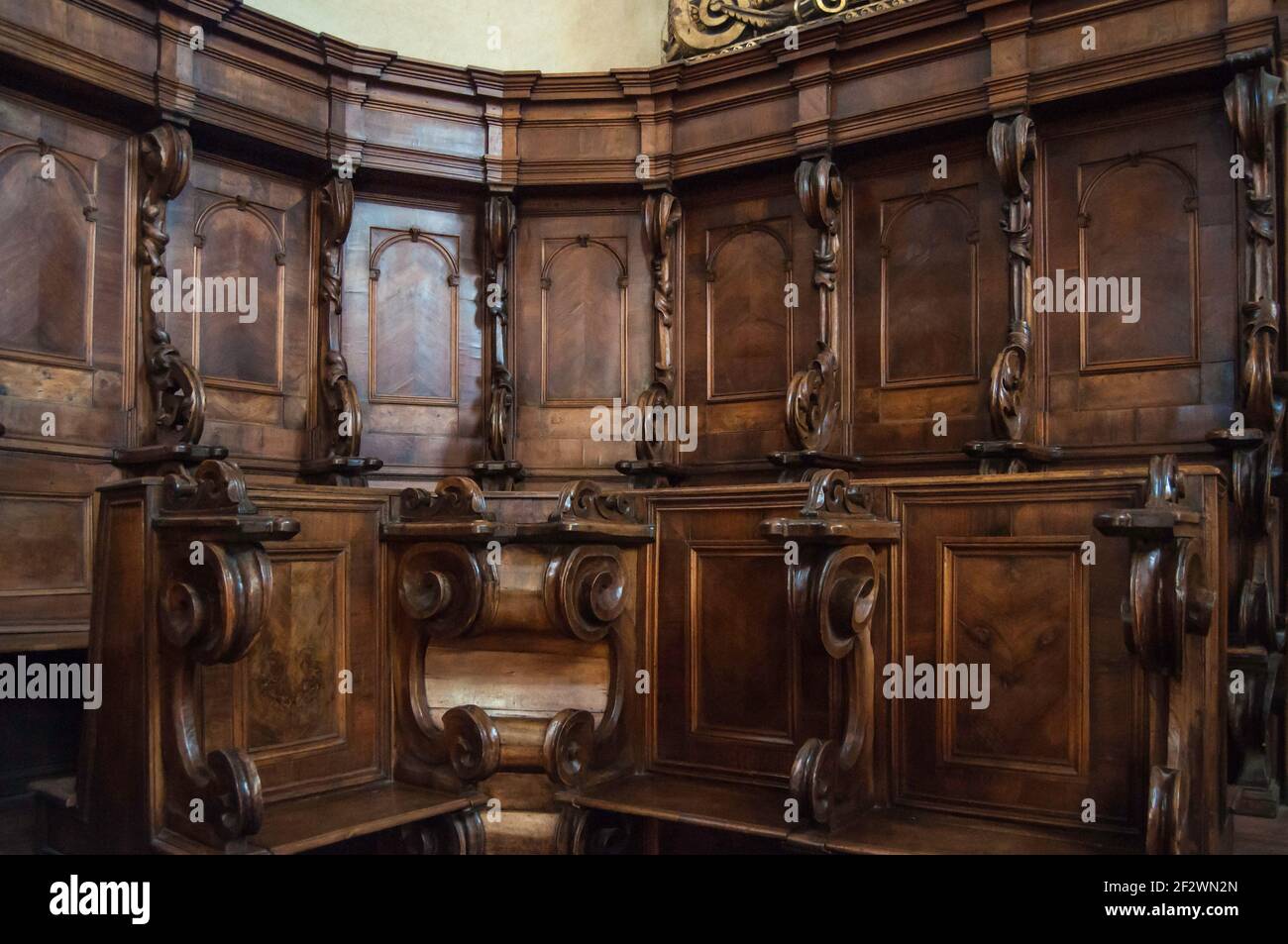 Detail of an old  carved bench in a church in Italy. Frontal view of the corner of the bench. There are many beautiful details to be seen Stock Photo