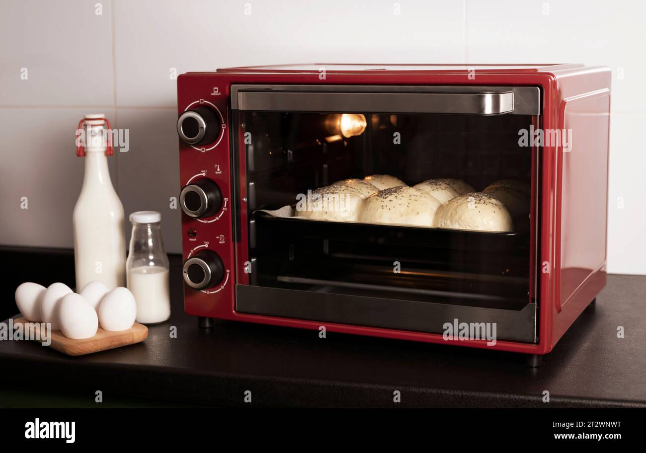 homemade yeast buns are baked in a red oven. there are ingredients