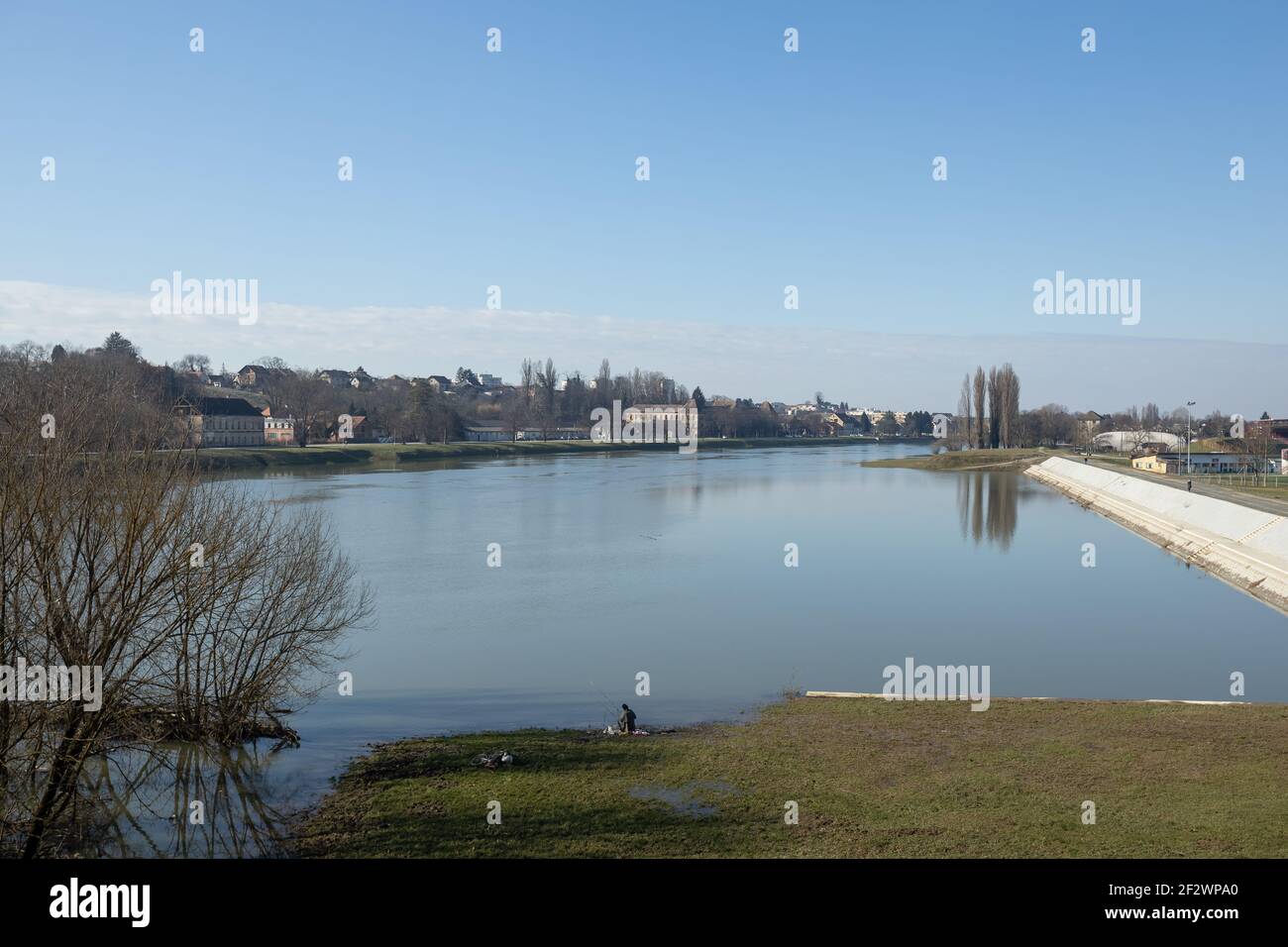 View of the river Kupa and a man fishing along the shore in Sisak. Stock Photo