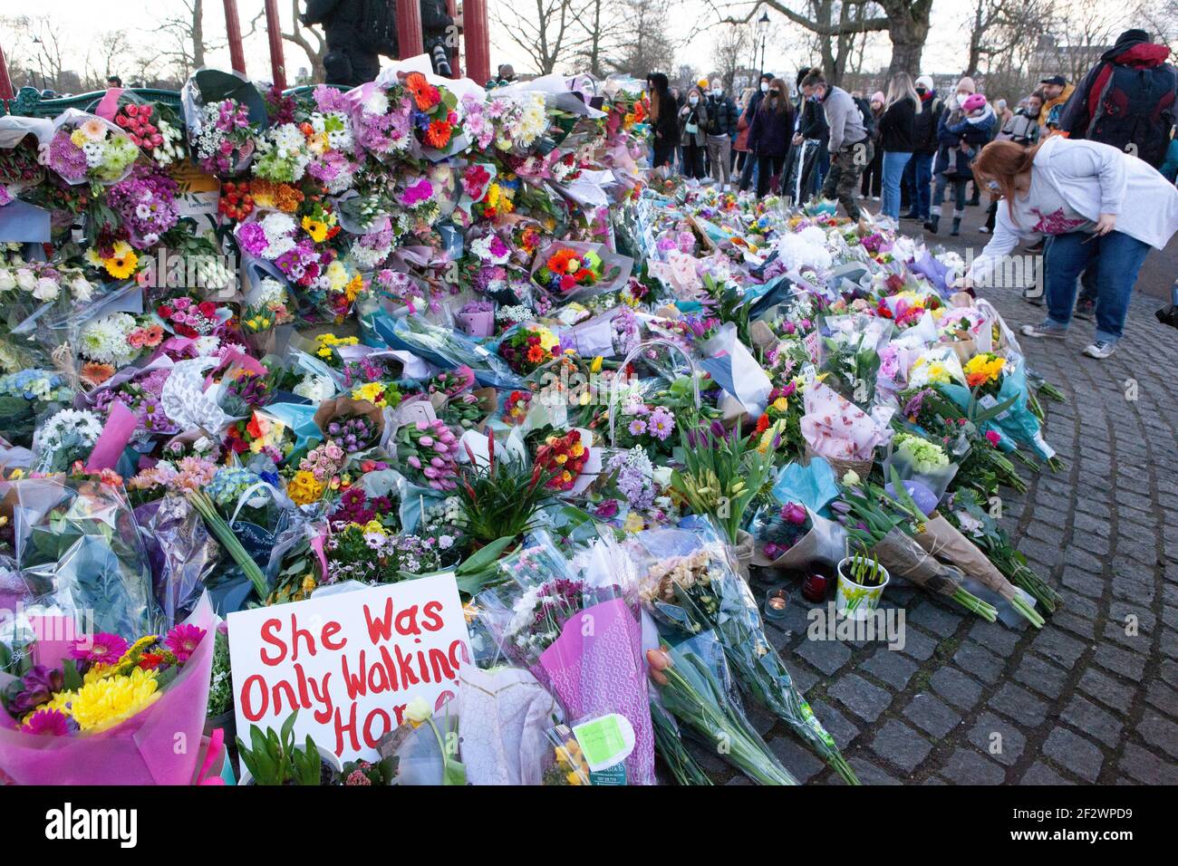 London, UK, 13 March 2021: A memorial of flowers for Sarah Everard draws hundreds of well wishers at Clapham Common bandstand. Tributes included plants, flowers, candles and messages such as 'When Will Women be Safe?' and 'She was only walking home.' An official vigil has been cancelled due to police concerns over coronavirus. Anna Watson/Alamy Live News Stock Photo