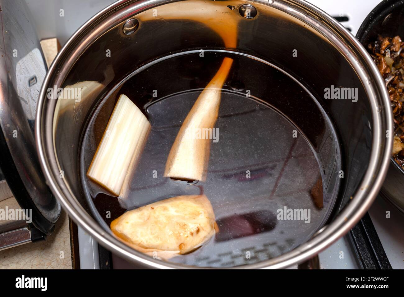 Mushroom soup decoction with celery, leek and spices in a steel pot on