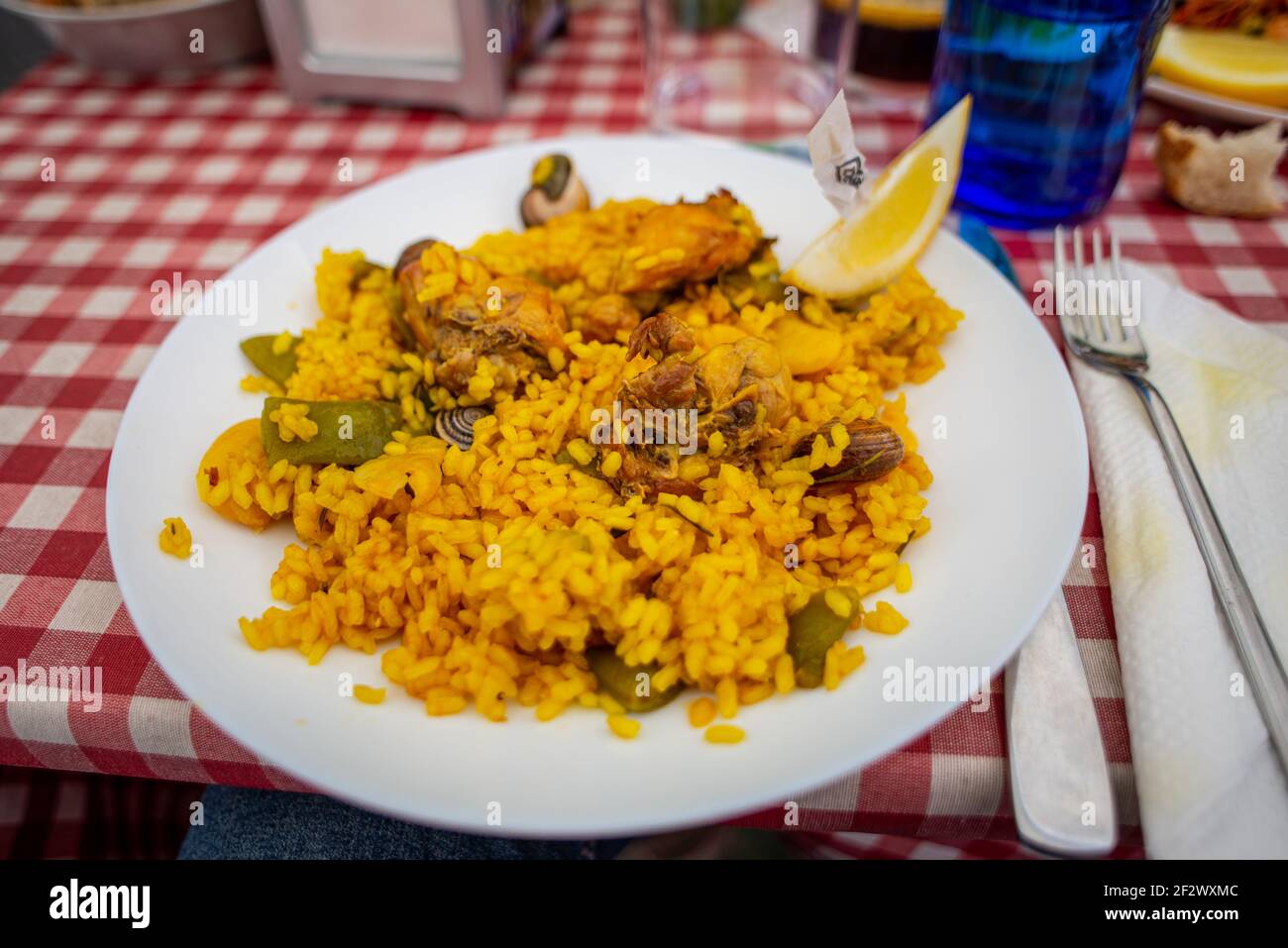 Traditional paella valenciana served in a restaurant in Velancia. It's a popular rice-based dish with seafood and chicken Stock Photo