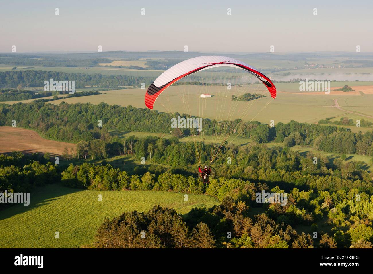 In morning, one paramotor flying over the fields in Yonne department, in Bourgogne-Franche-comté region, France - Stock Image