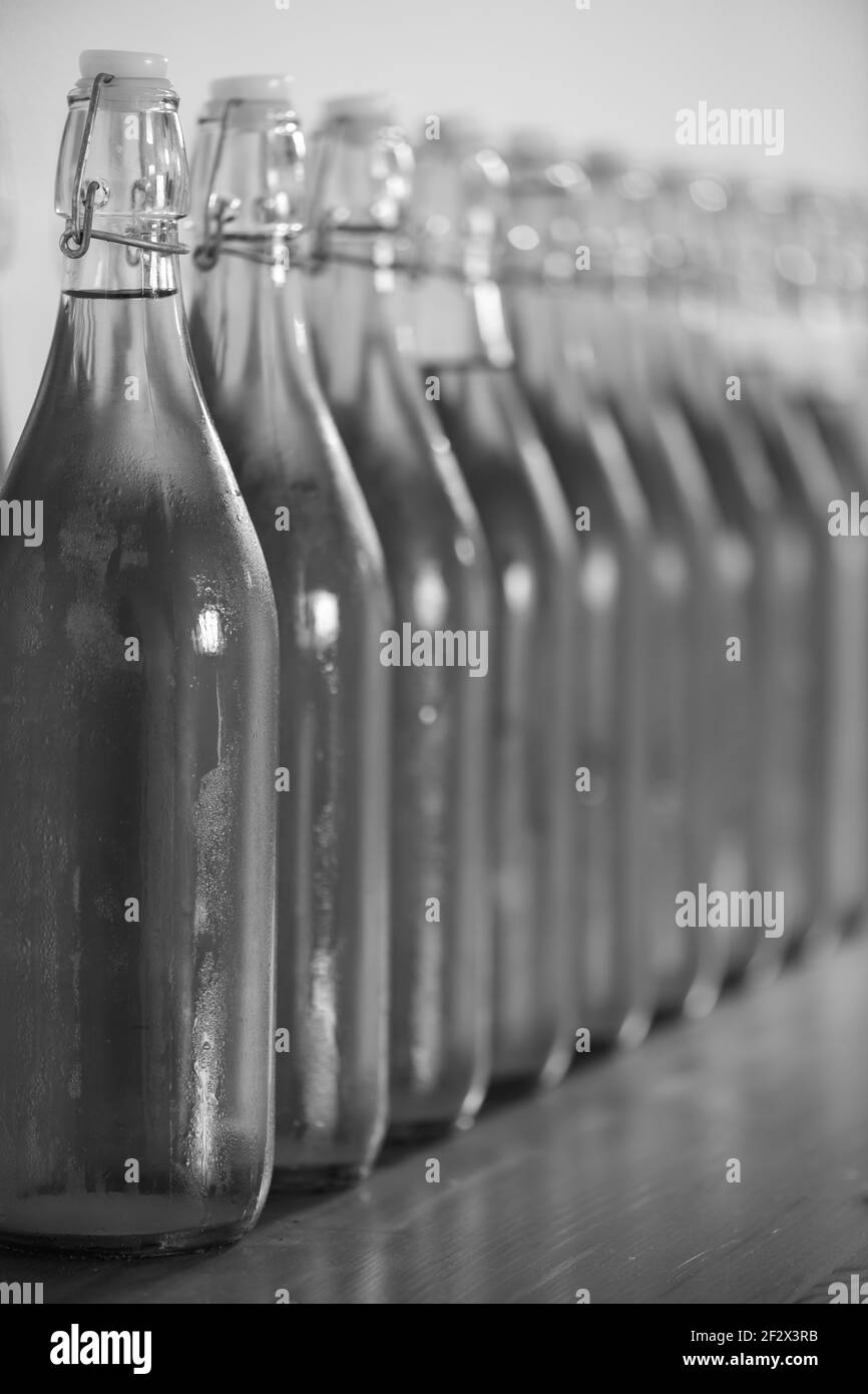 Black and white photo of a row of flip top bottles of home made cider covered in condensation Stock Photo