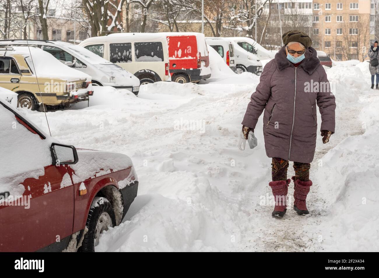 Lutsk, Ukraine - February 12,2020: City street after blizzard. Woman wearing face mask on public street in middle of coronavirus epidemic in winter Stock Photo