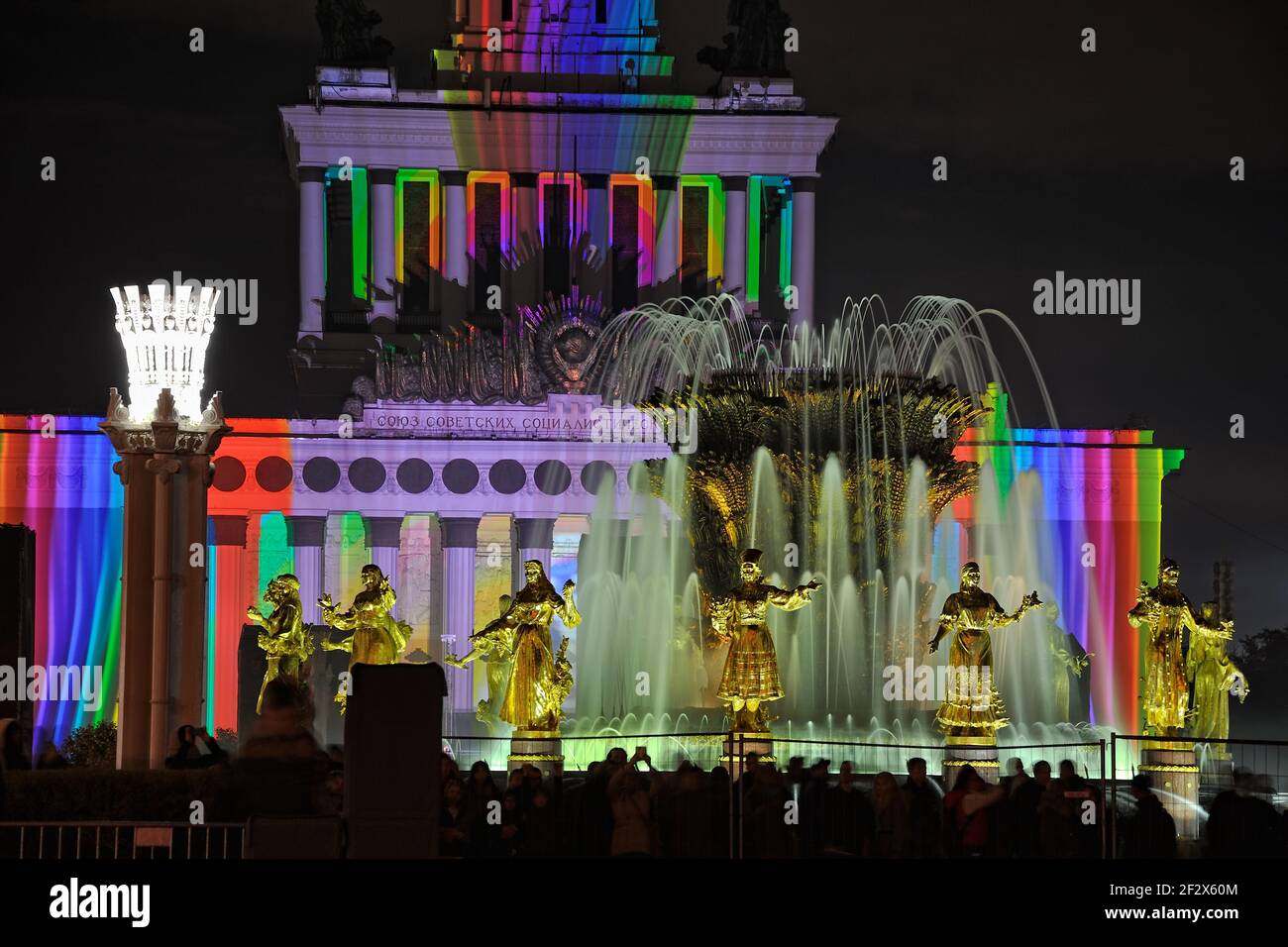 = Fountain of Nations and Projection Mapping on the Central Pavilion =  Gilded sculptures of the fountain “Friendship of Nations” and the colorful str Stock Photo