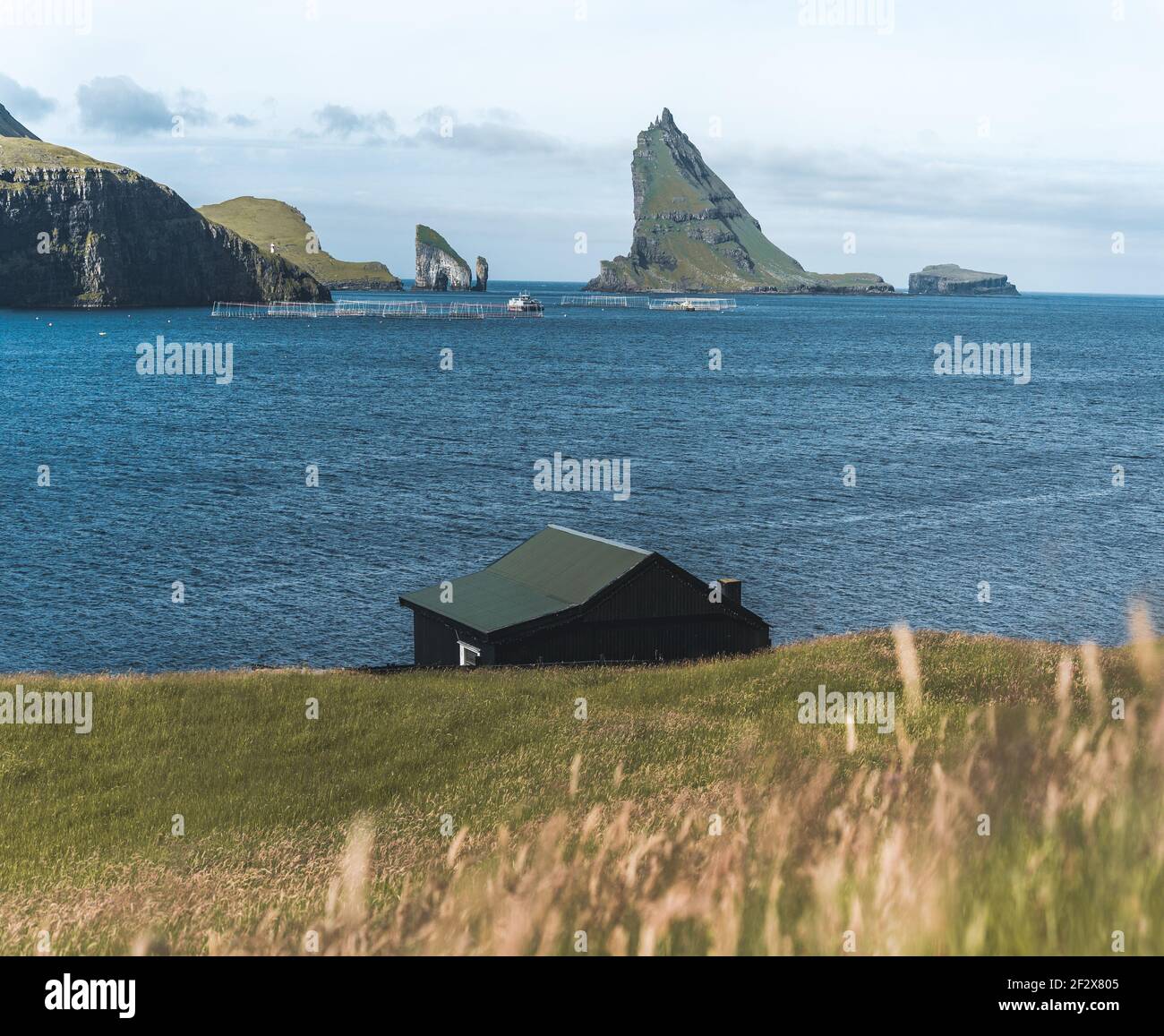 Small village house in front of Drangarnir gate and Tindholmur and mykines island in the background, Faroe Islands. Stock Photo