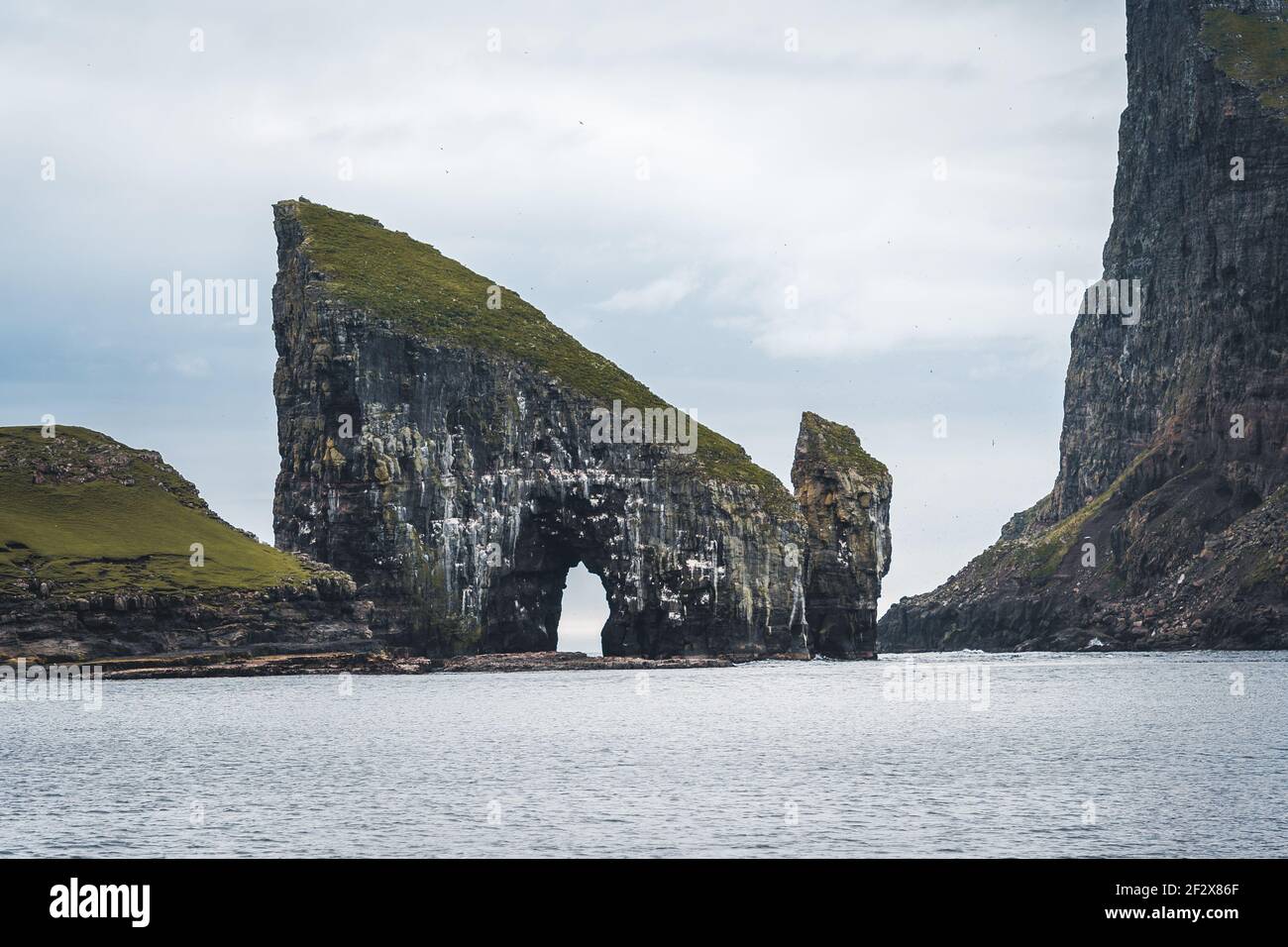 Close-up shot of famous Drangarnir cliff with Tindholmur islands in the background taken during early morning hike in spring at Faroese coastline Stock Photo
