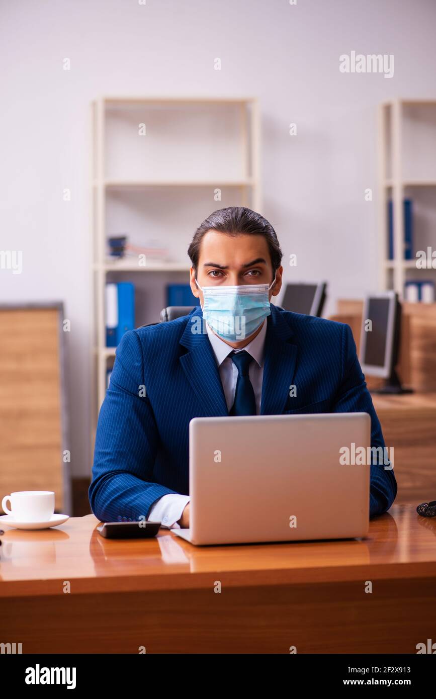 Young employee working in the office wearing mask Stock Photo - Alamy