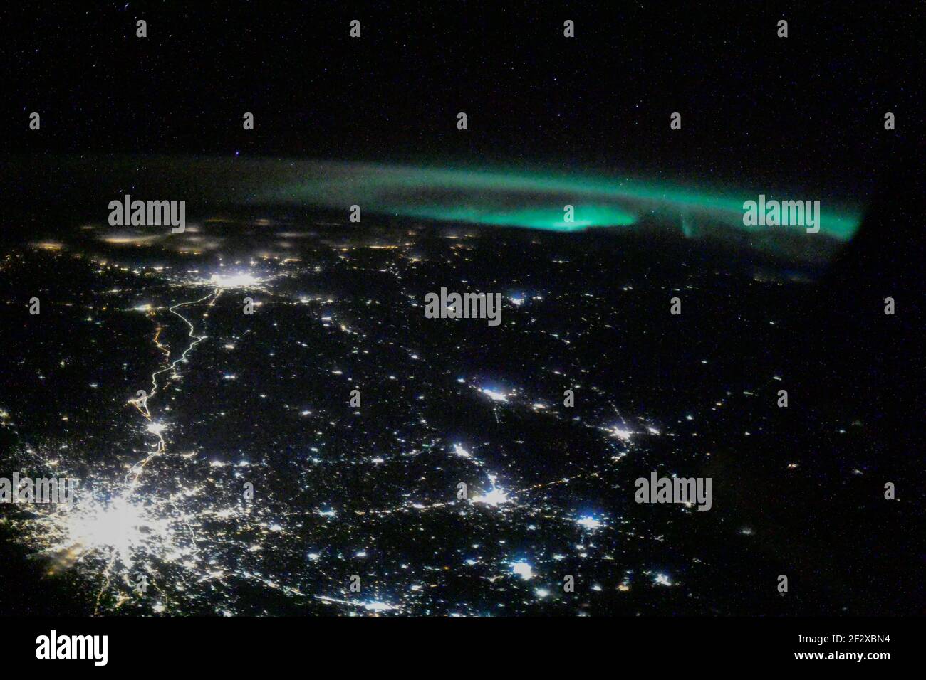 The city lights of Moscow and its suburbs seemingly branch out towards an aurora seen from the International Space Station as it orbited 263 miles above February 26, 2021 in Earth Orbit. Stock Photo