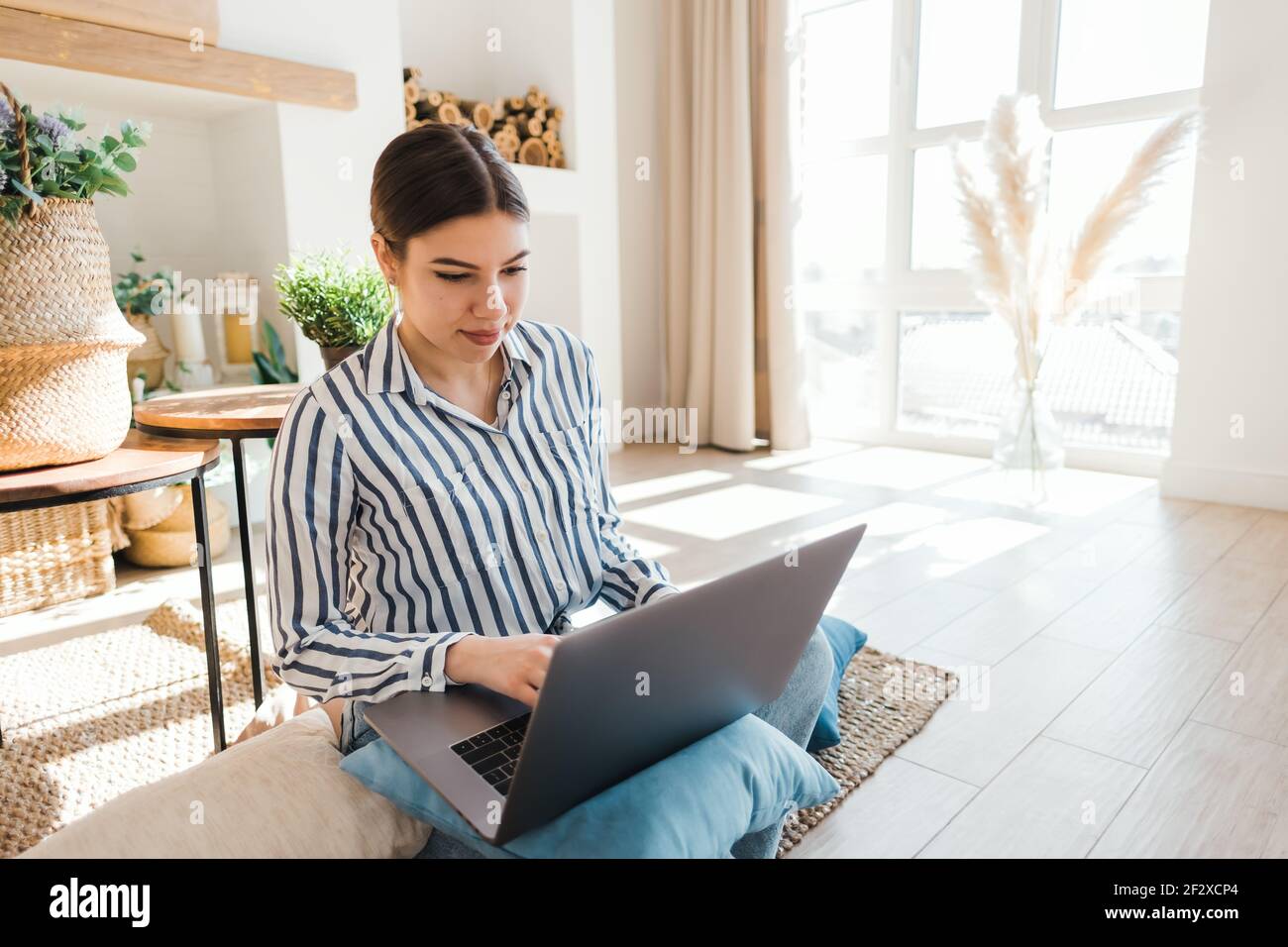 Young caucasian woman working on laptop in cozy living room, sitting on ...