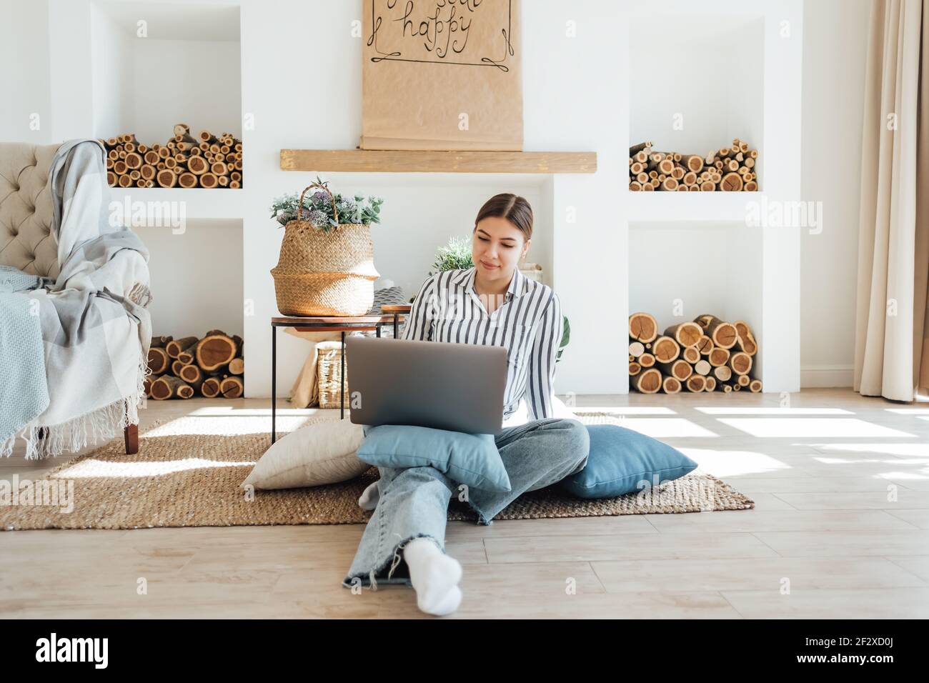 Young caucasian woman working on laptop in cozy living room, sitting on ...