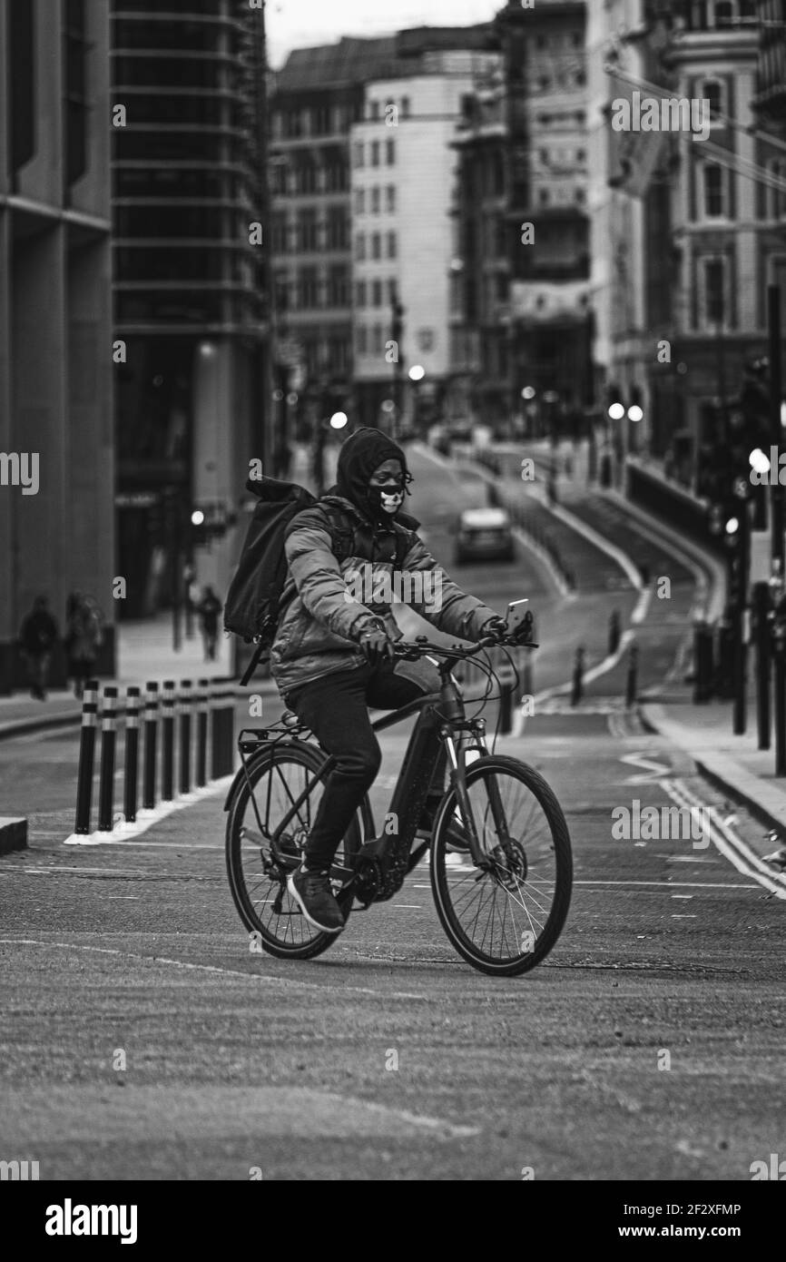 London UK February 2021 Vertical black and white shot of a cyclist crossing the street in downtown London, cold winter day during UKs covid national l Stock Photo