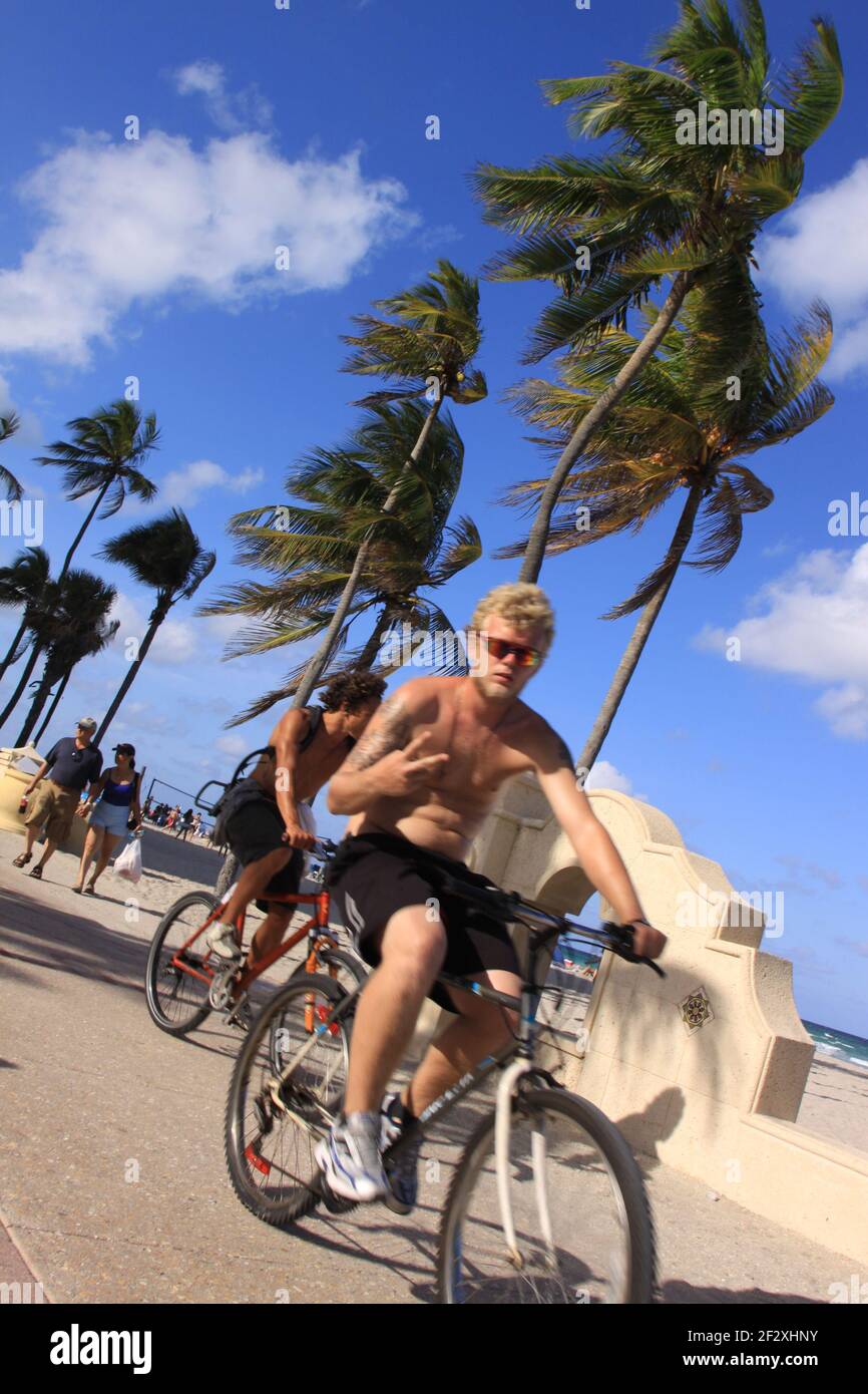 Young men riding bicycle on the Hollywood Beach Broadwalk in Hollywood, Florida. Photo by Sean Drakes/Alamy Stock Photo