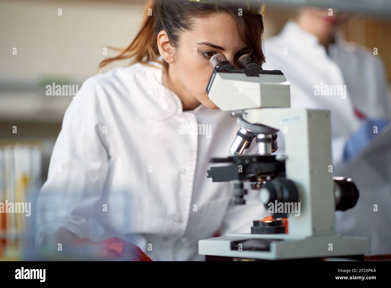 A young female student using a microscope in a sterile laboratory environment. Science