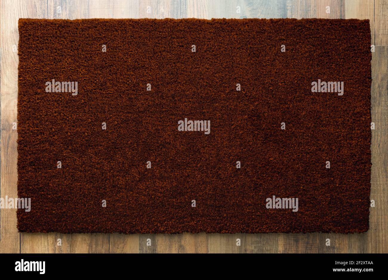 Blank Dark Brown Welcome Mat On Wood Floor Background Ready For Your Own Text. Stock Photo