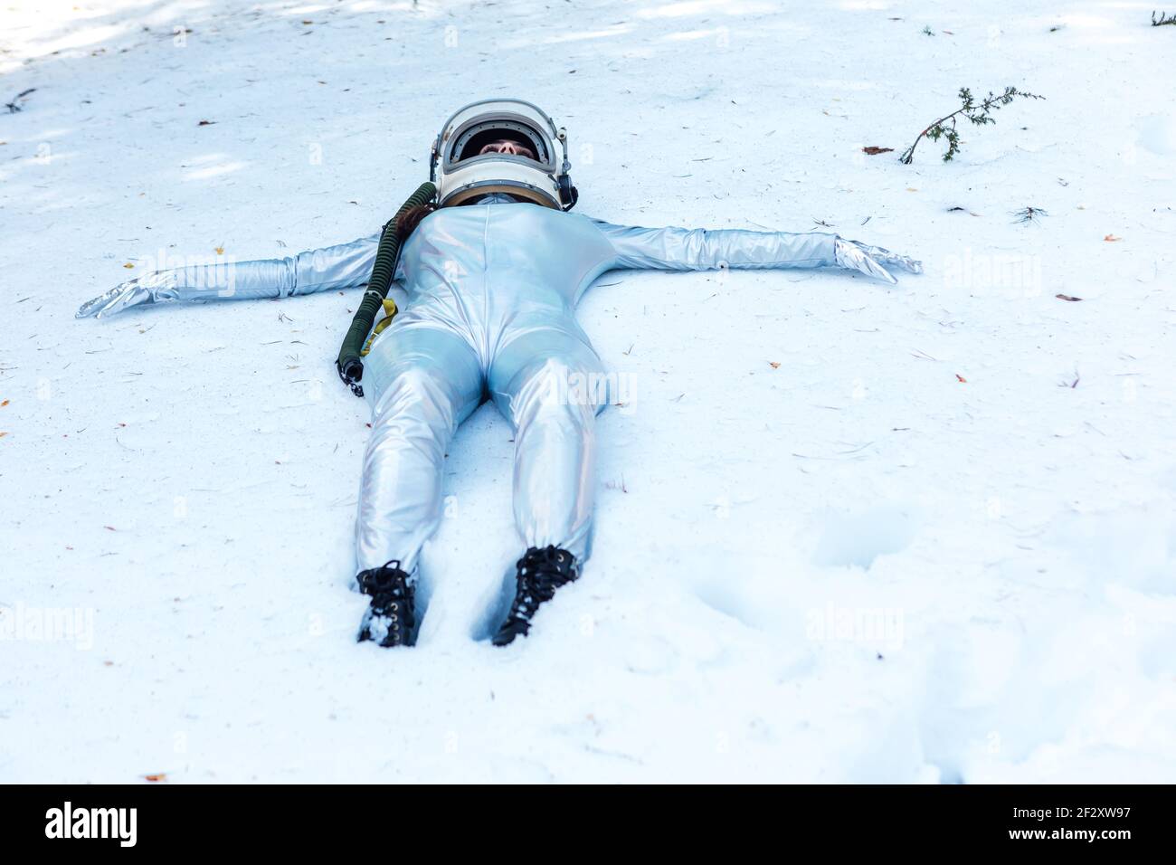 Full body fit calm spaceWoman in costume and helmet lying with arms outstretched on snowy glade in winter forest Stock Photo