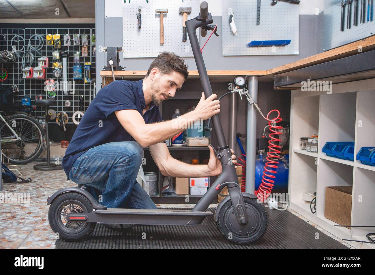 Side view of skilled adult male mechanic fixing electric scooter in modern  service workshop Stock Photo - Alamy