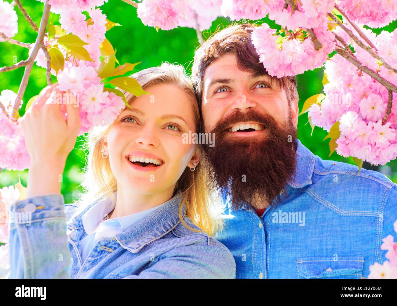 Relationship concept. Happy Couple near blossoming Sakura. Smiling family spend time in spring garden. Stock Photo