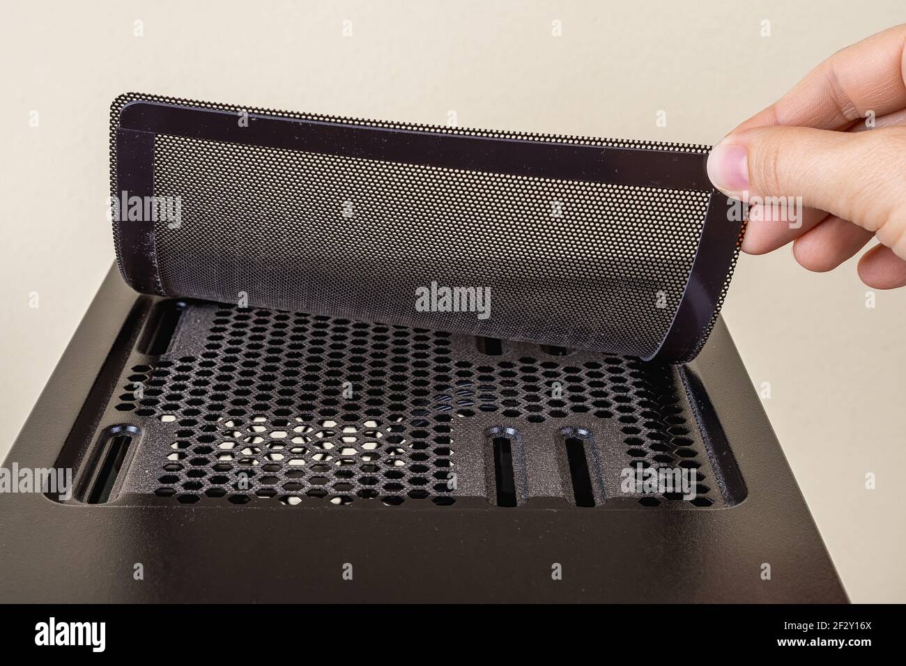 Hand lifted the top fan cooling filter on the black computer tower case