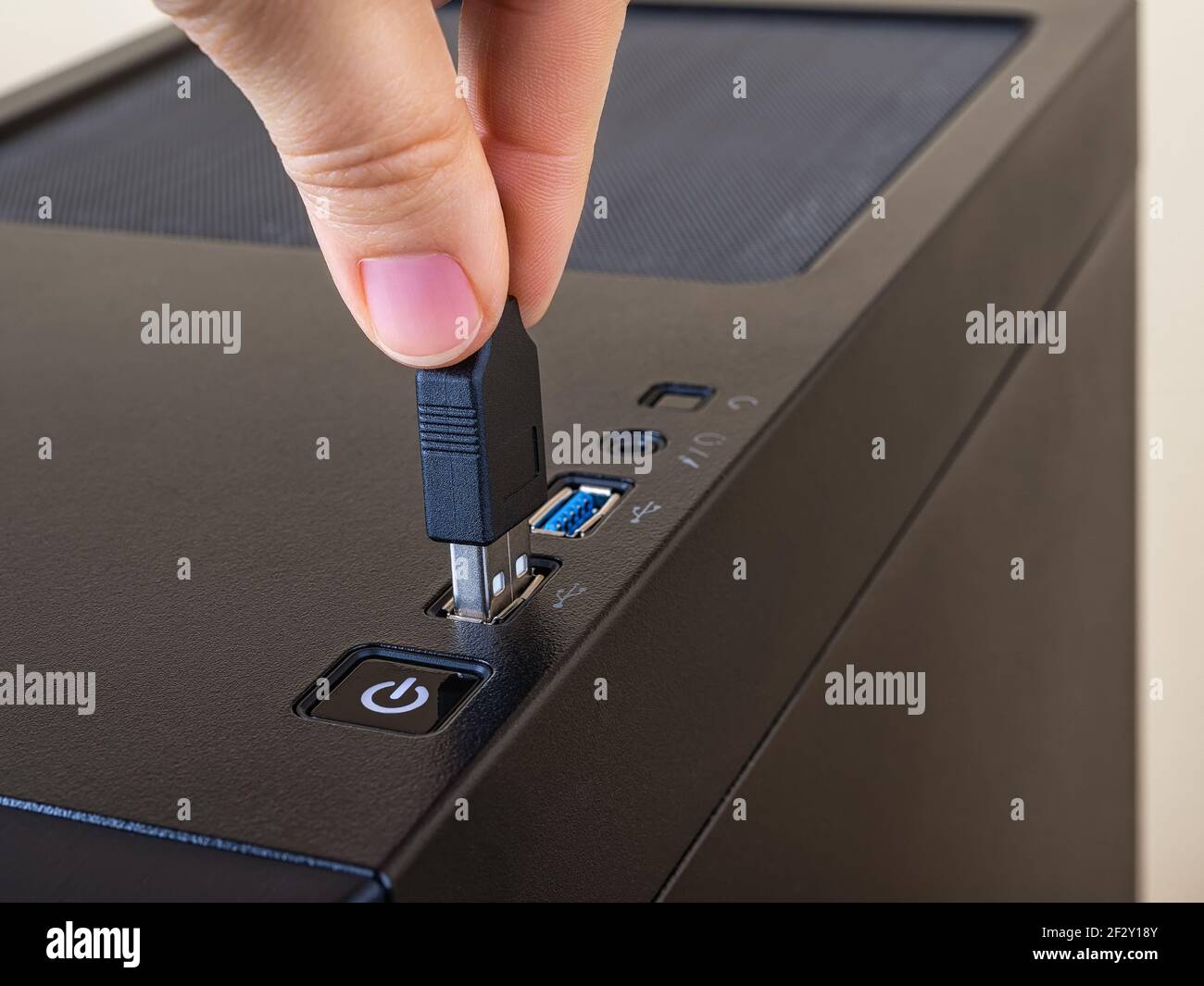 Person fingers insert the USB cable into the top port on the computer tower case. Information transfer and storage device. USB connectors standard. Stock Photo