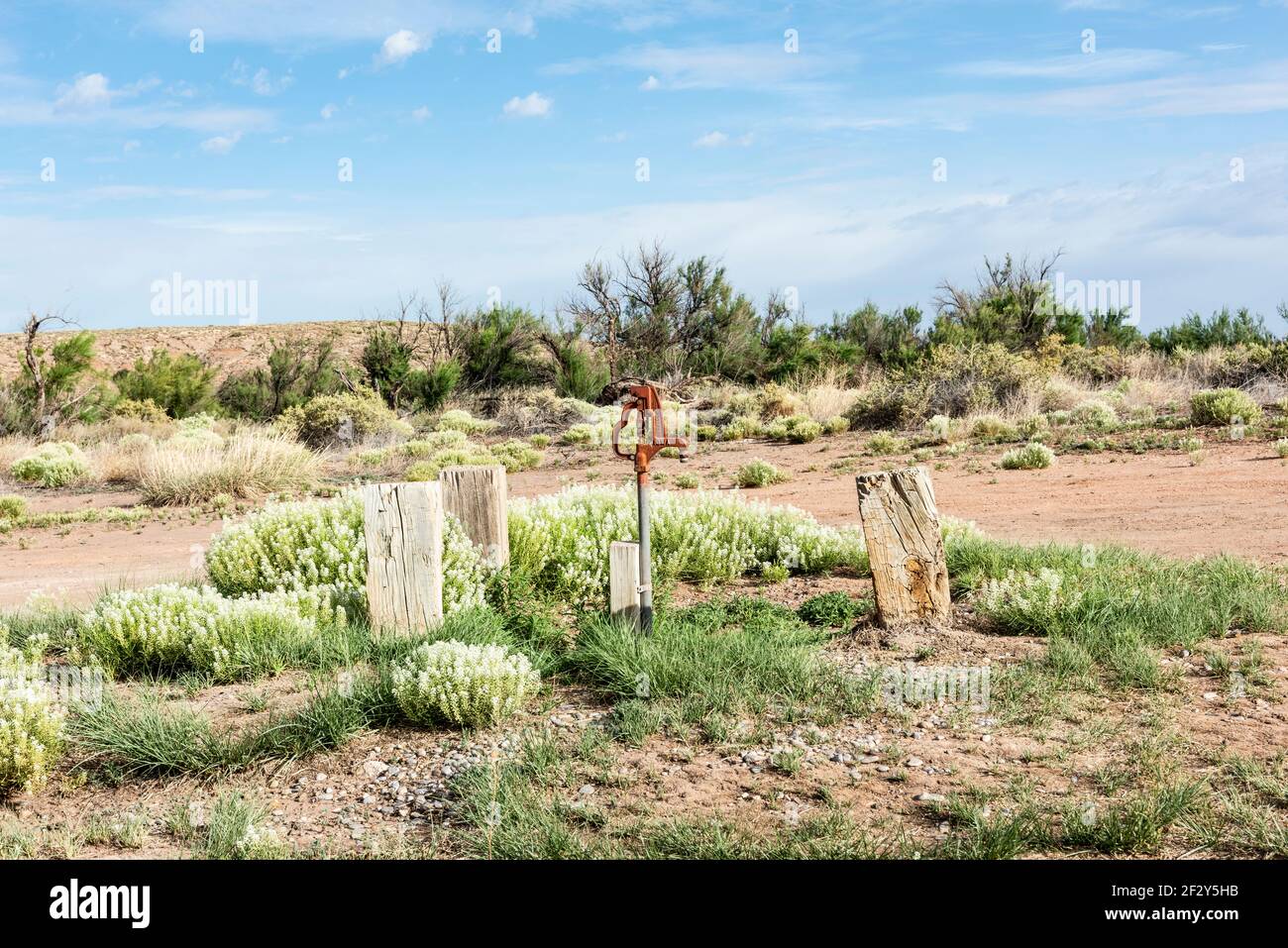 Bright orange colored hand water pump set against the semi-arid desert landscape of a rustic campground in the Bottomless Lakes State Park, New Mexico Stock Photo