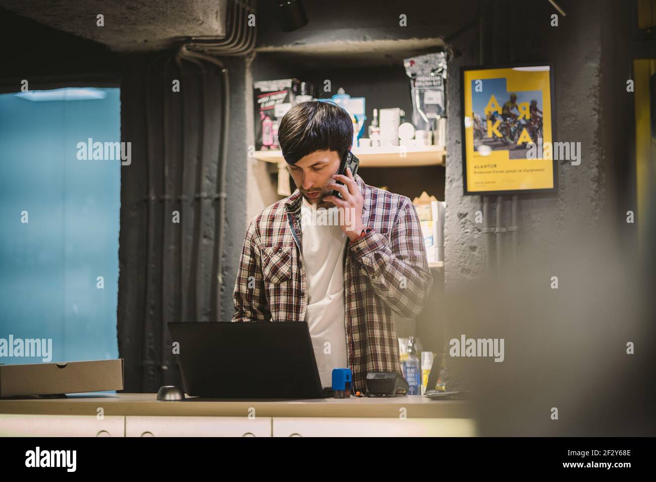 Small business owner on phone and computer in store. Sport shop worker  making call with cell phone. Salesman working and talking on cell phone in  Stock Photo - Alamy