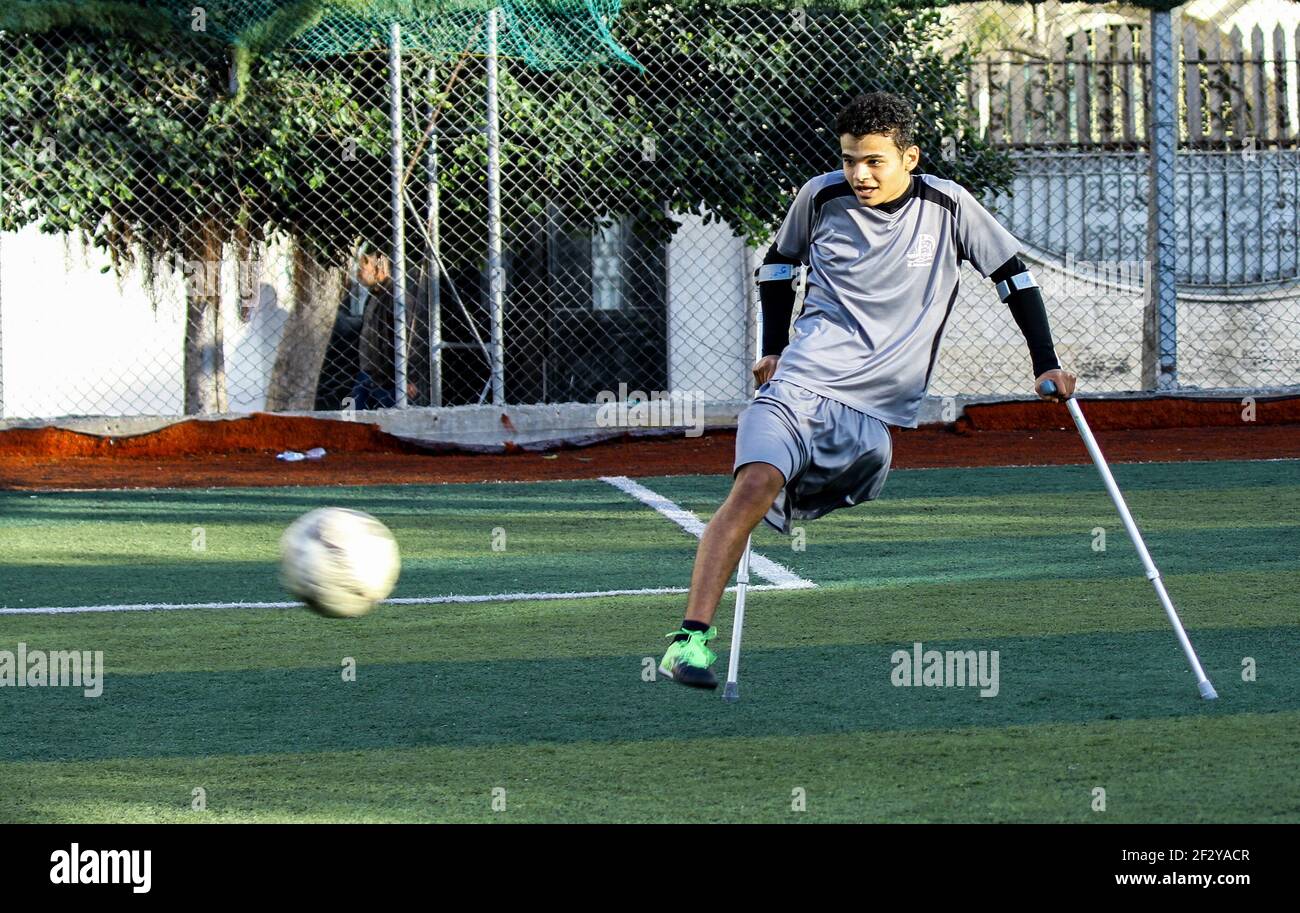 March 13, 2021: Gaza, Palestine. 13 March 2021. Palestinians with crutches play football in the Al-Jazeera Club in Gaza City on the 'Palestinian Day of the injured''. The players have lost a leg either in Israeli attacks on Gaza or in the March of Return demonstrations, during which they were shot to their limbs by Israeli soldiers based at the perimeter fence with Gaza. Some of the severe limb gunshot wounds have required complex limb reconstruction treatments, while others have required amputation. Yet, despite losing a leg, many Palestinians have not lost their resilience and determinati Stock Photo