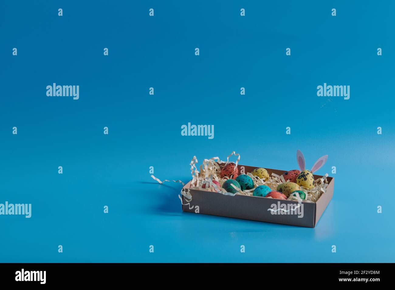 colored eggs in a box on a blue background Stock Photo