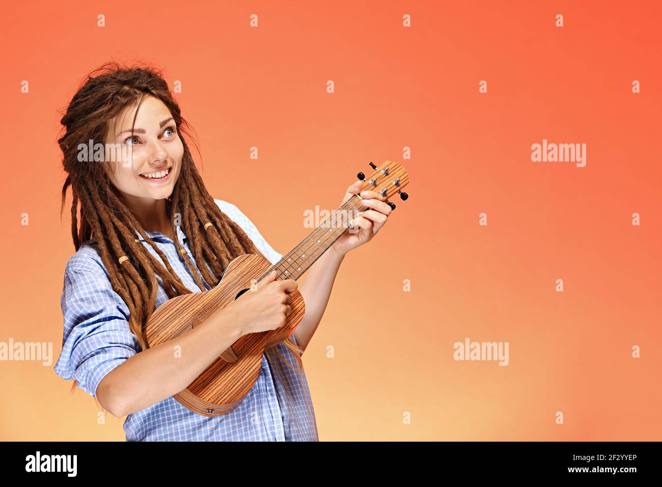 Portrait of funny young woman playing ukulele. Happiness and carefree concept Stock Photo