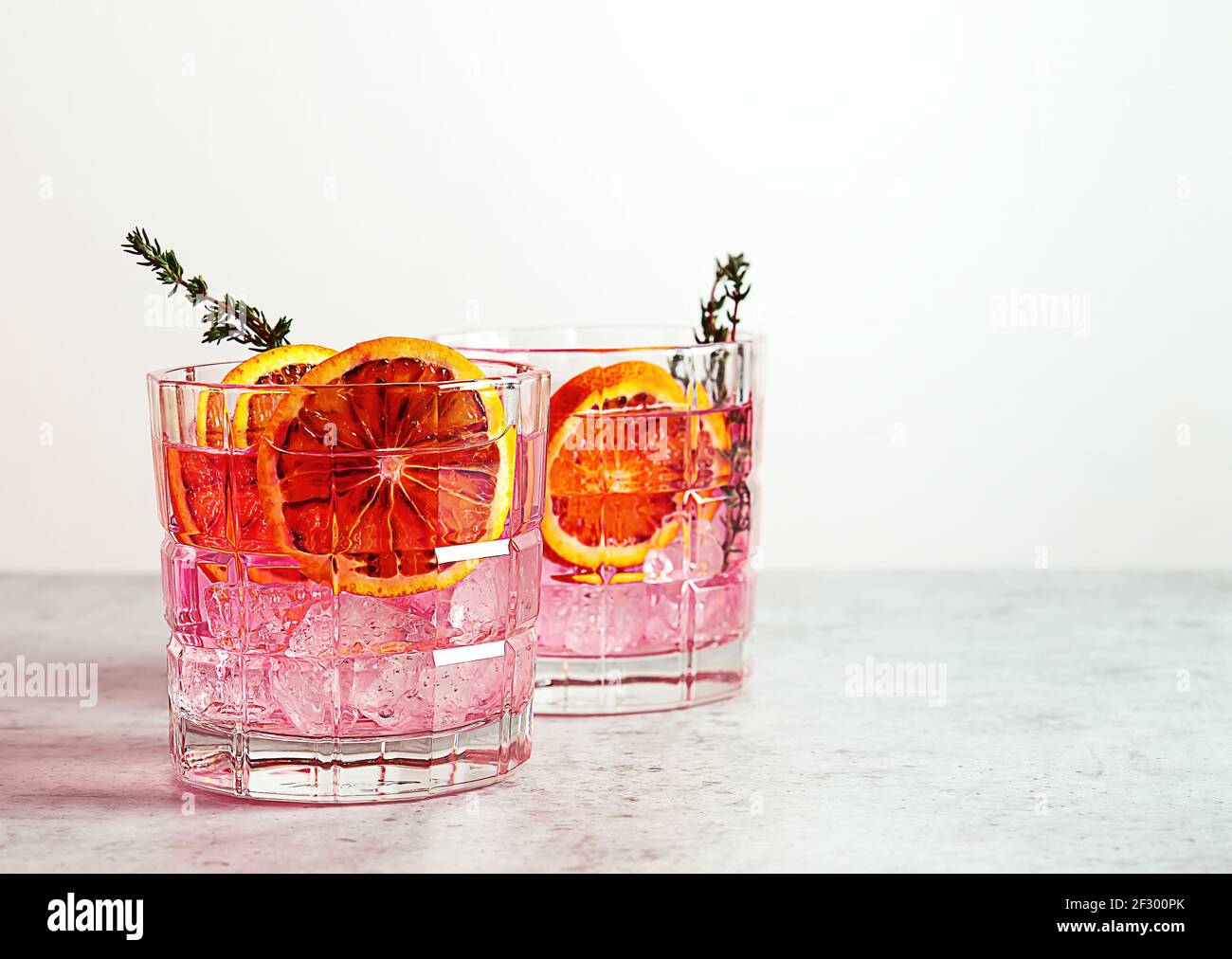 Pink gin cocktail with red blood orange and ice. An alcoholic