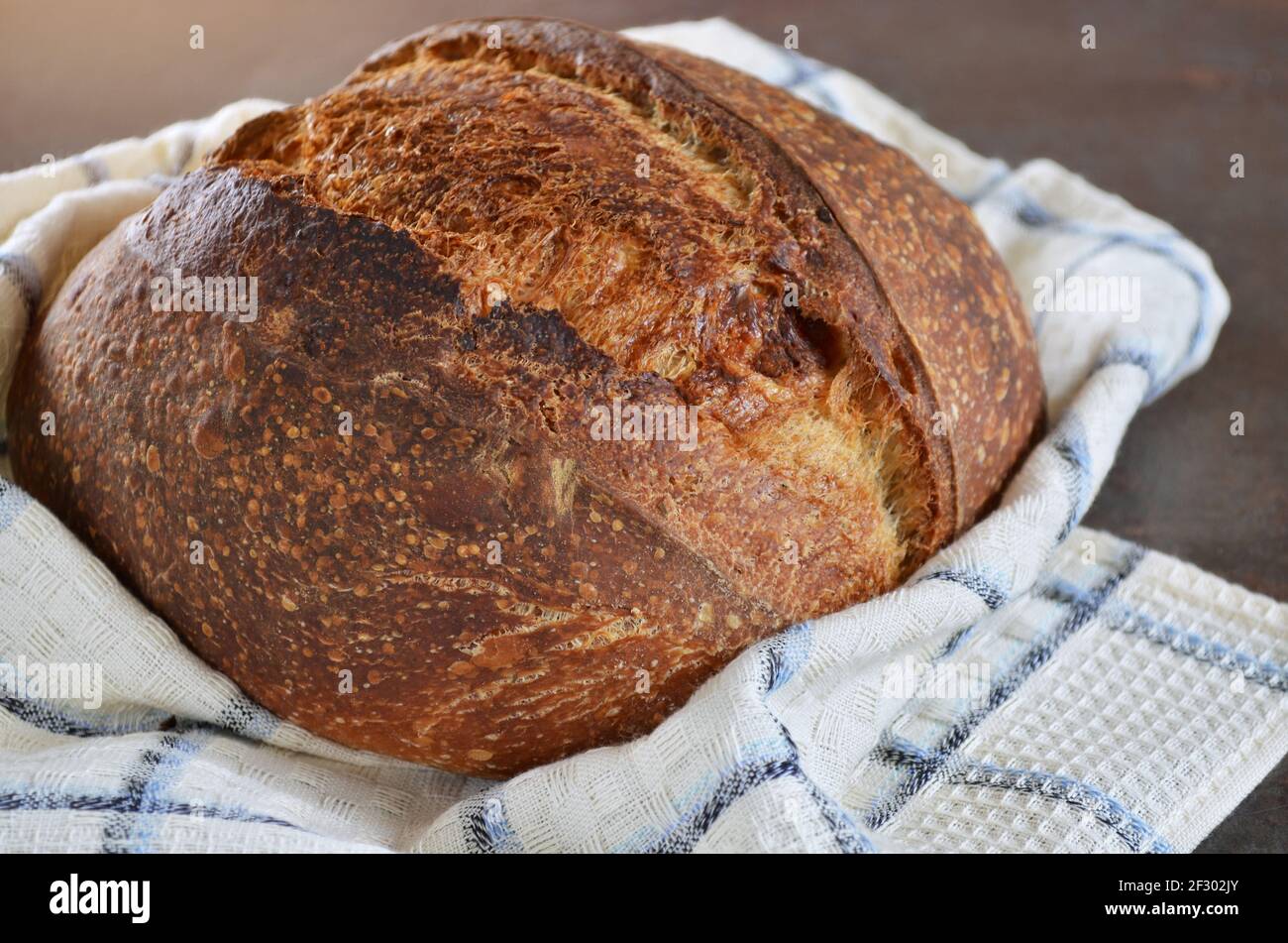 Freshly baked loaf of sourdough bread on a kitchen towel close-up Stock Photo