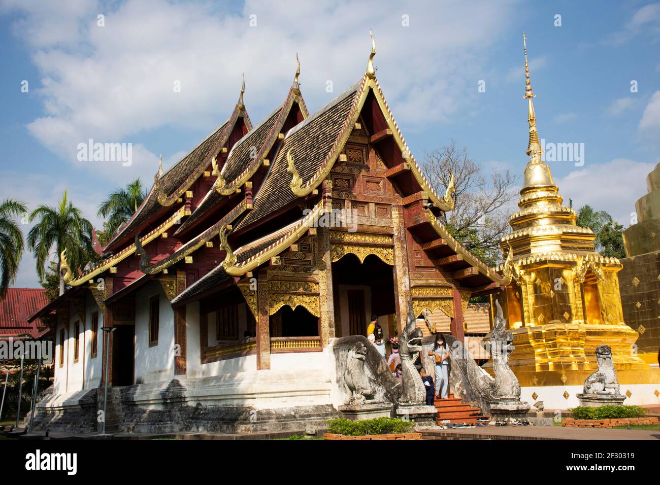 Thai people and foreign traveler travel visit respect praying buddha god angel deity and relics golden chedi stupa at  Wat Phra Singh Woramahaviharn T Stock Photo