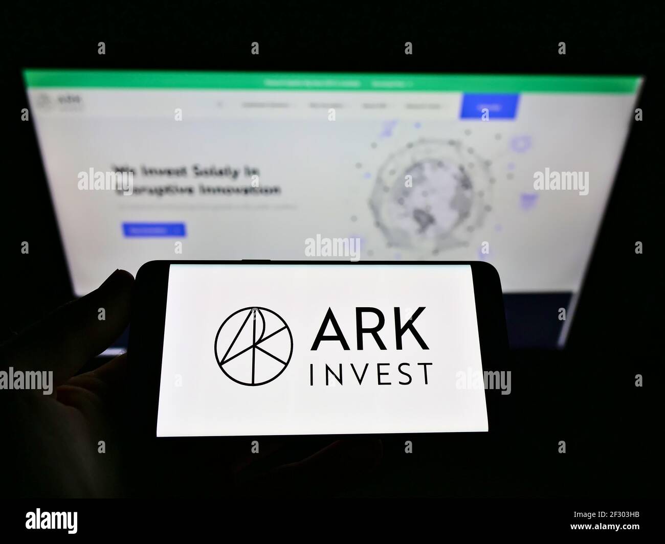 Person holding cellphone with company logo of US asset manager ARK Investment Management LLC on screen in front of webpage. Focus on phone display. Stock Photo