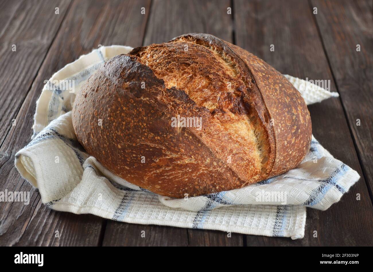 Rustic sourdough bread with a crisp crust on a kitchen towel close-up Stock Photo