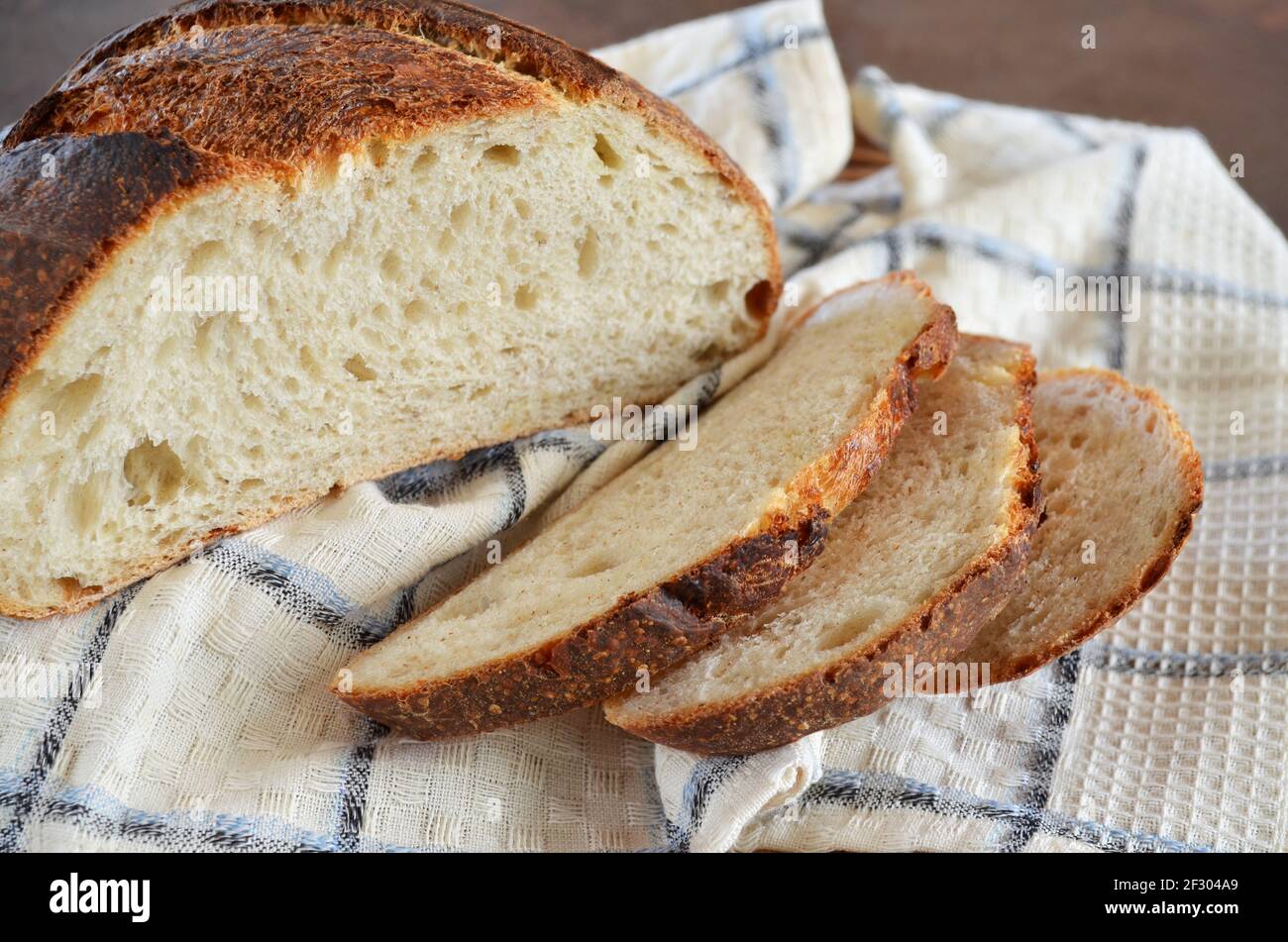 Sliced sourdough bread with a crisp crust on a kitchen towel close-up, selective focus Stock Photo