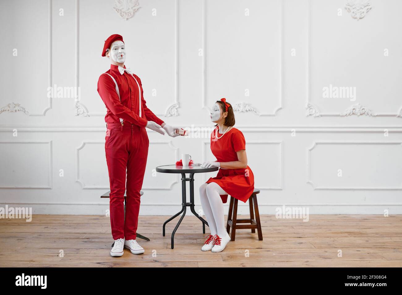 Two mime artists in red costumes, scene with gift Stock Photo - Alamy