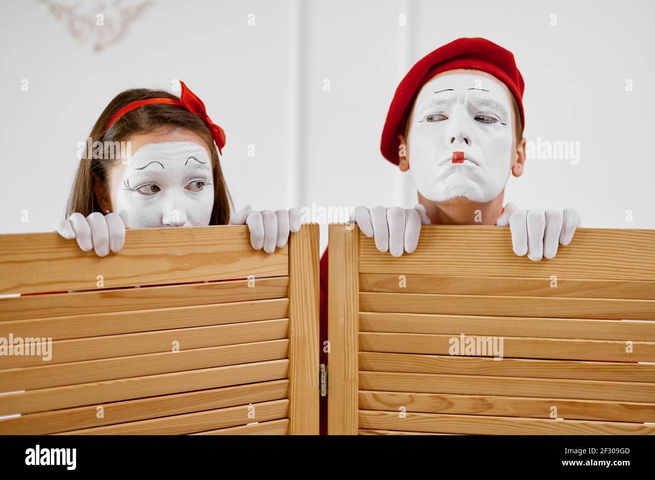 Two mime artists look out from partition Stock Photo - Alamy